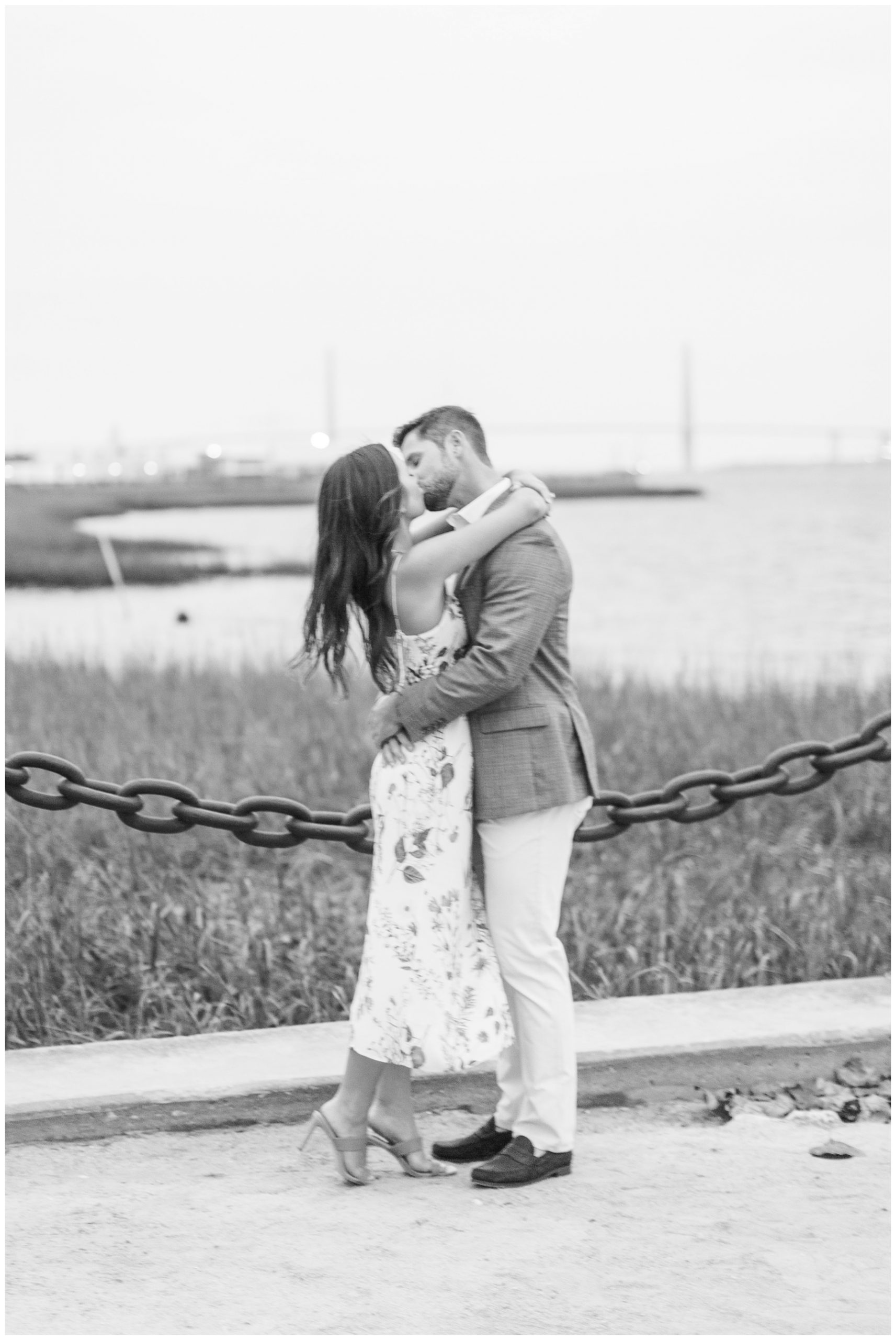 bride and groom kiss by chain link fence in Downtown Charleston along waterfront 