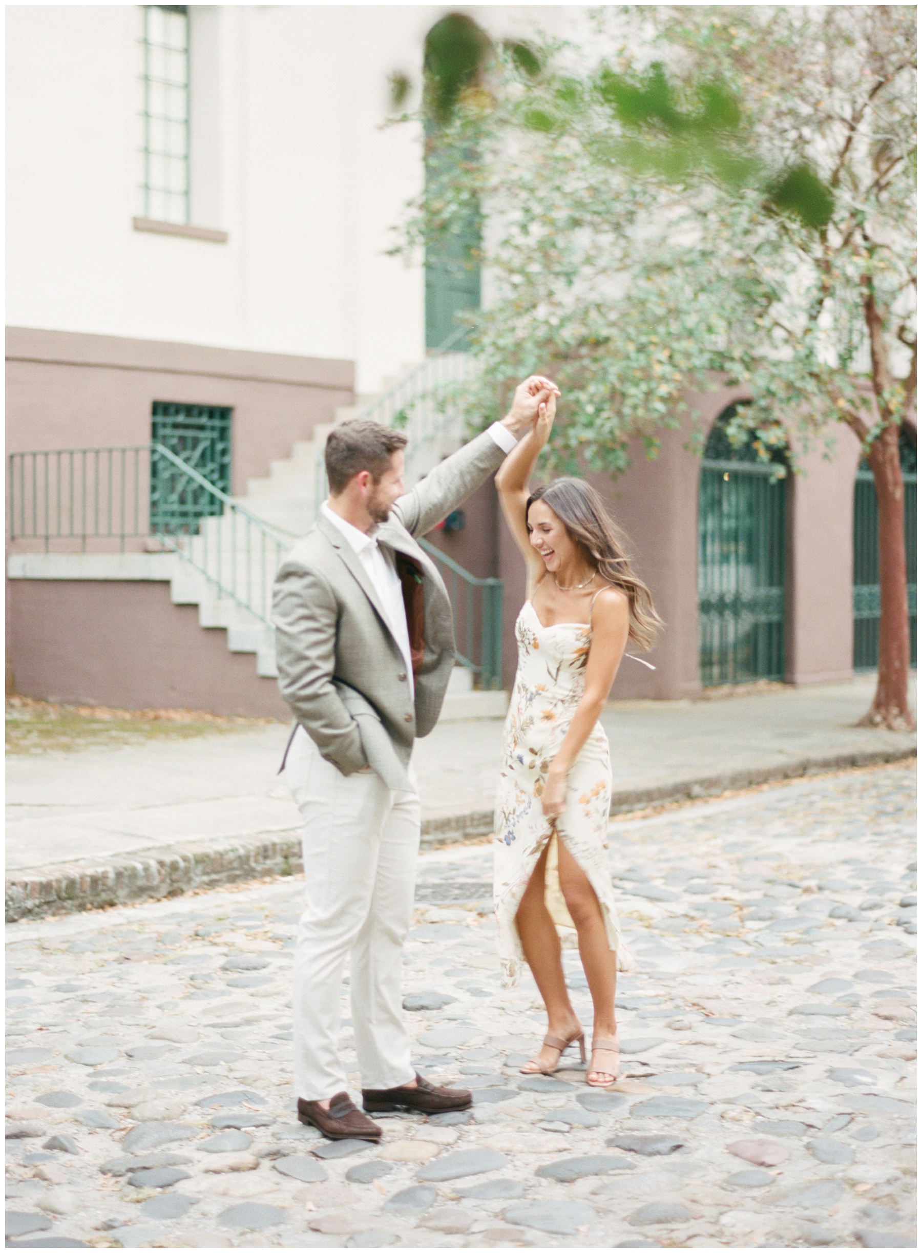 groom twirls bride on cobble stone streets in Downtown Charleston along Rainbow Row