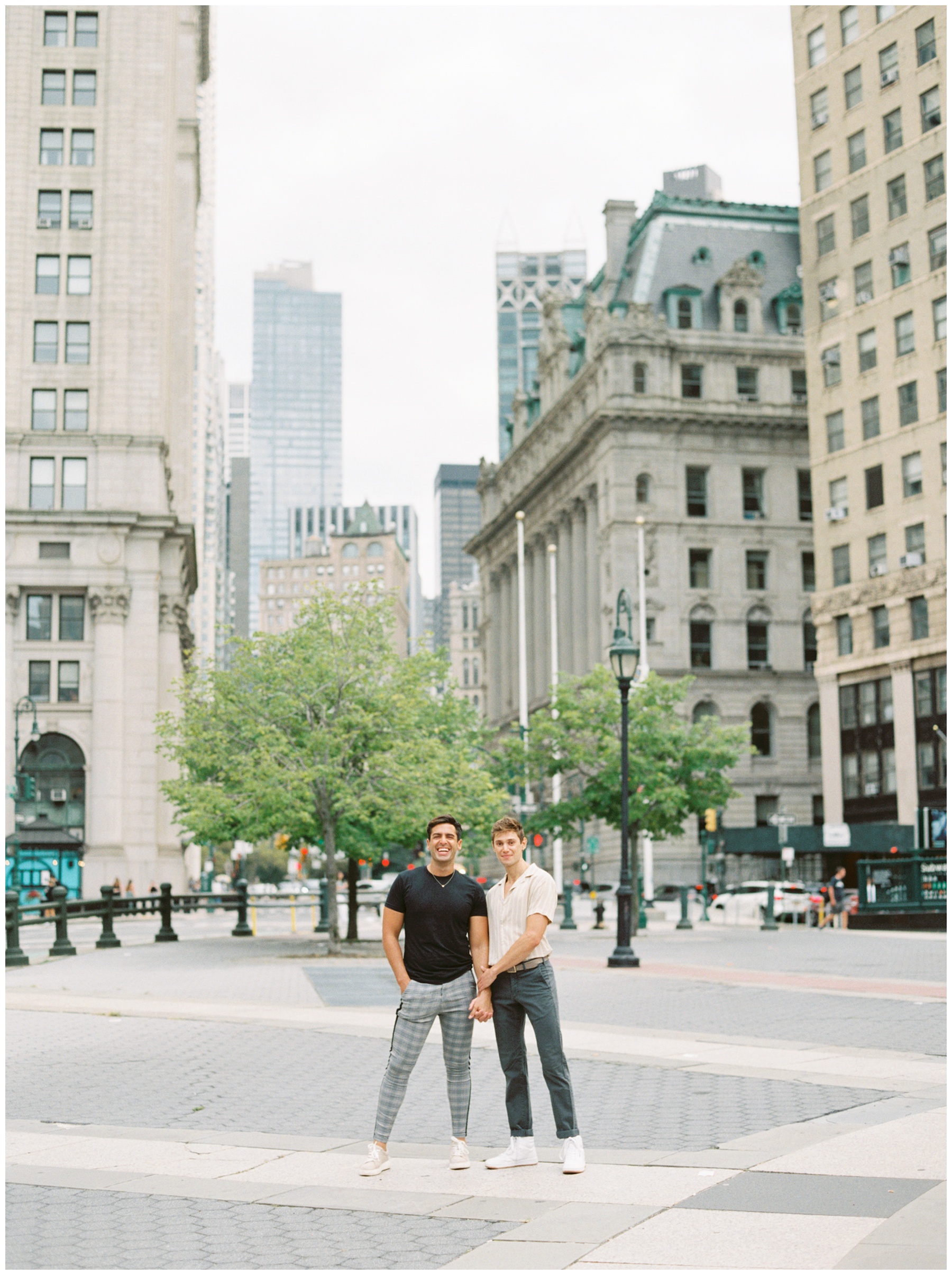 men hold hands in Foley Square during New York City engagement session