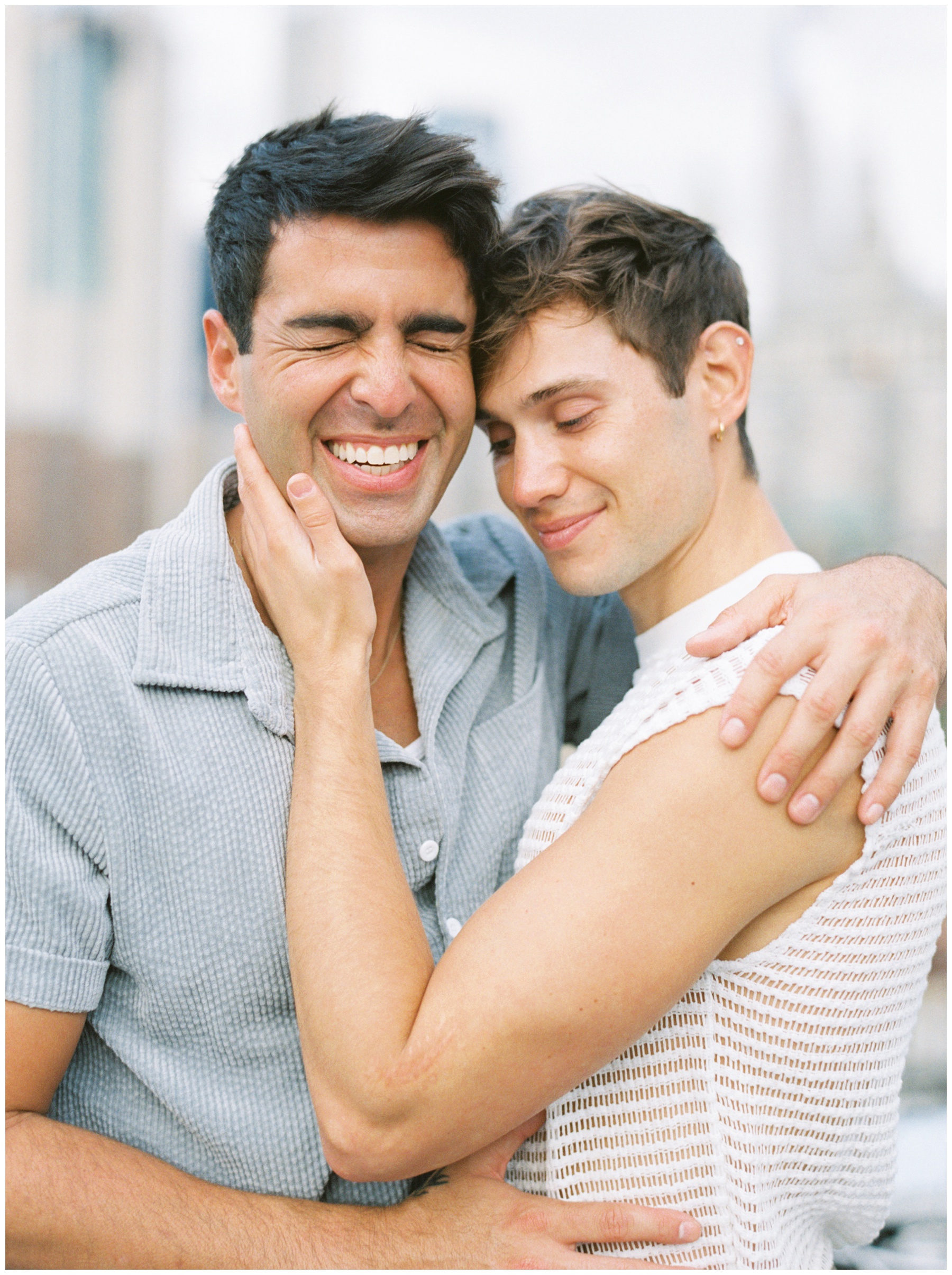men laugh while hugging during New York City engagement session