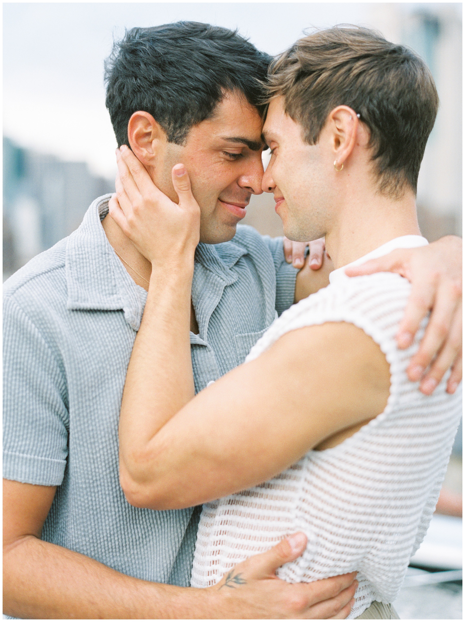 men hug leaning heads together nuzzling noses during New York City engagement session