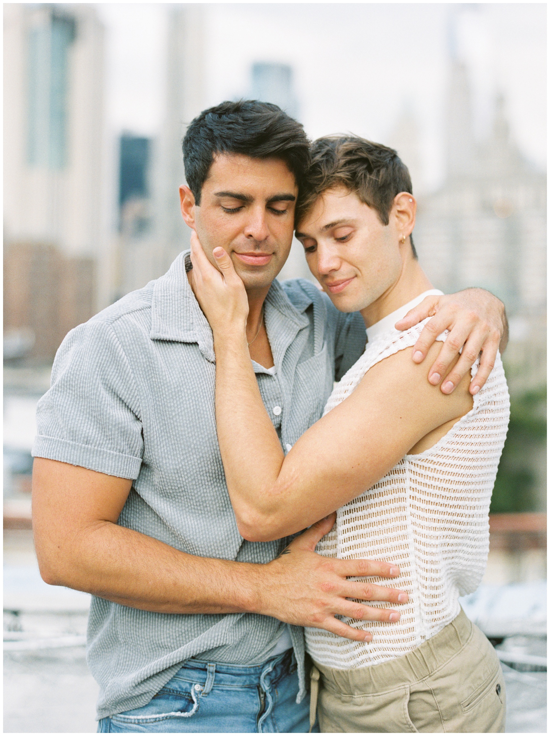 men hug leaning into each other in front of New York City skyline