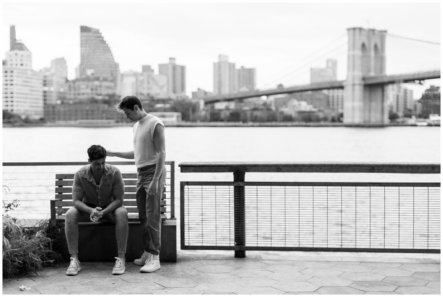man stands by boyfriend along Two Bridges waterfront during New York City engagement session