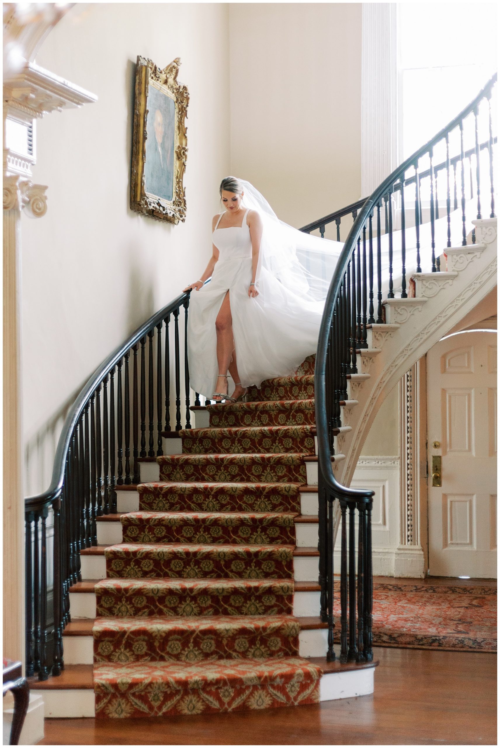 bride walks down staircase at the Governor Thomas Bennett House showing off slit in wedding dress skirt