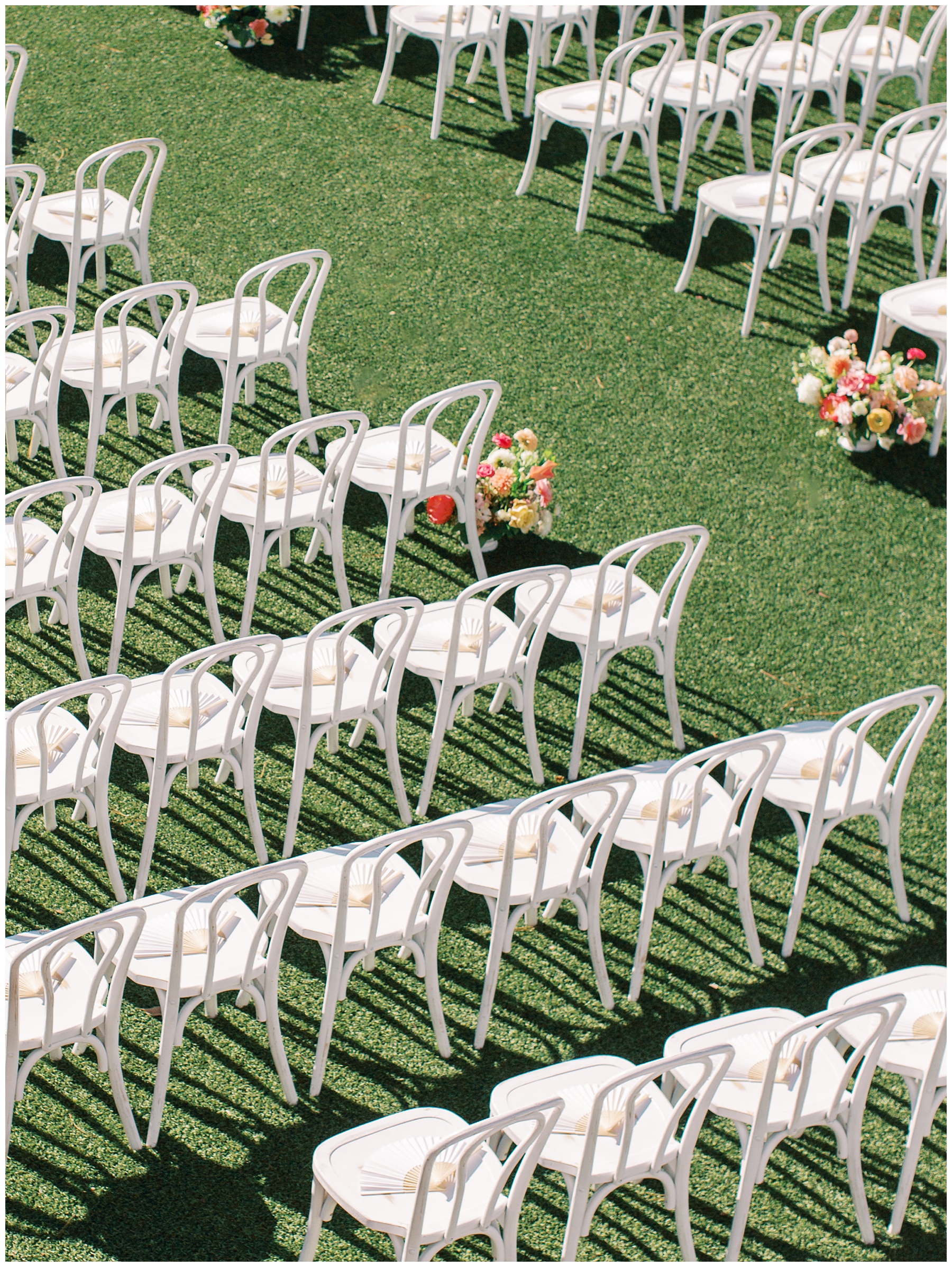 fans sit on white chairs for summer wedding ceremony at The Bradford