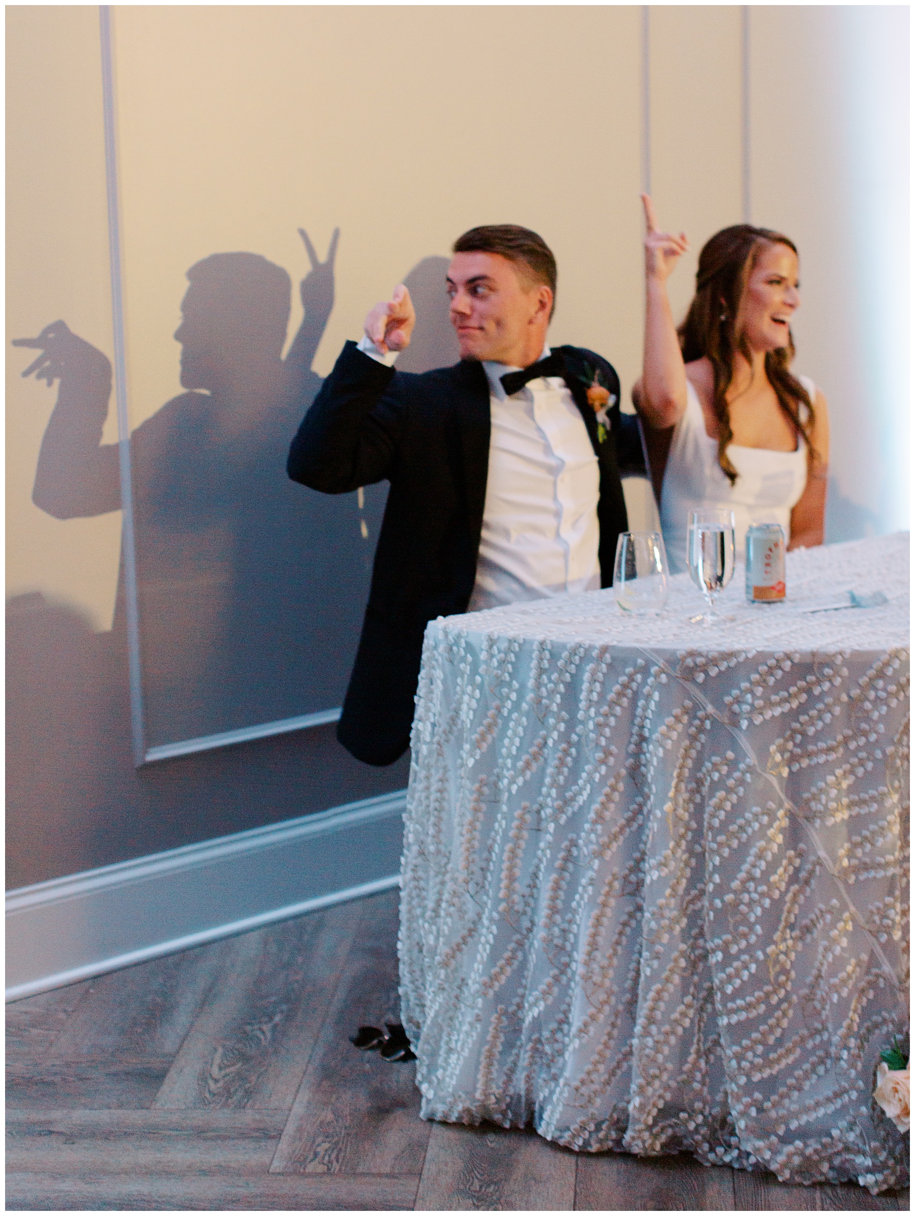 bride and groom make shadow puppets sitting at sweetheart table during reception at The Bradford