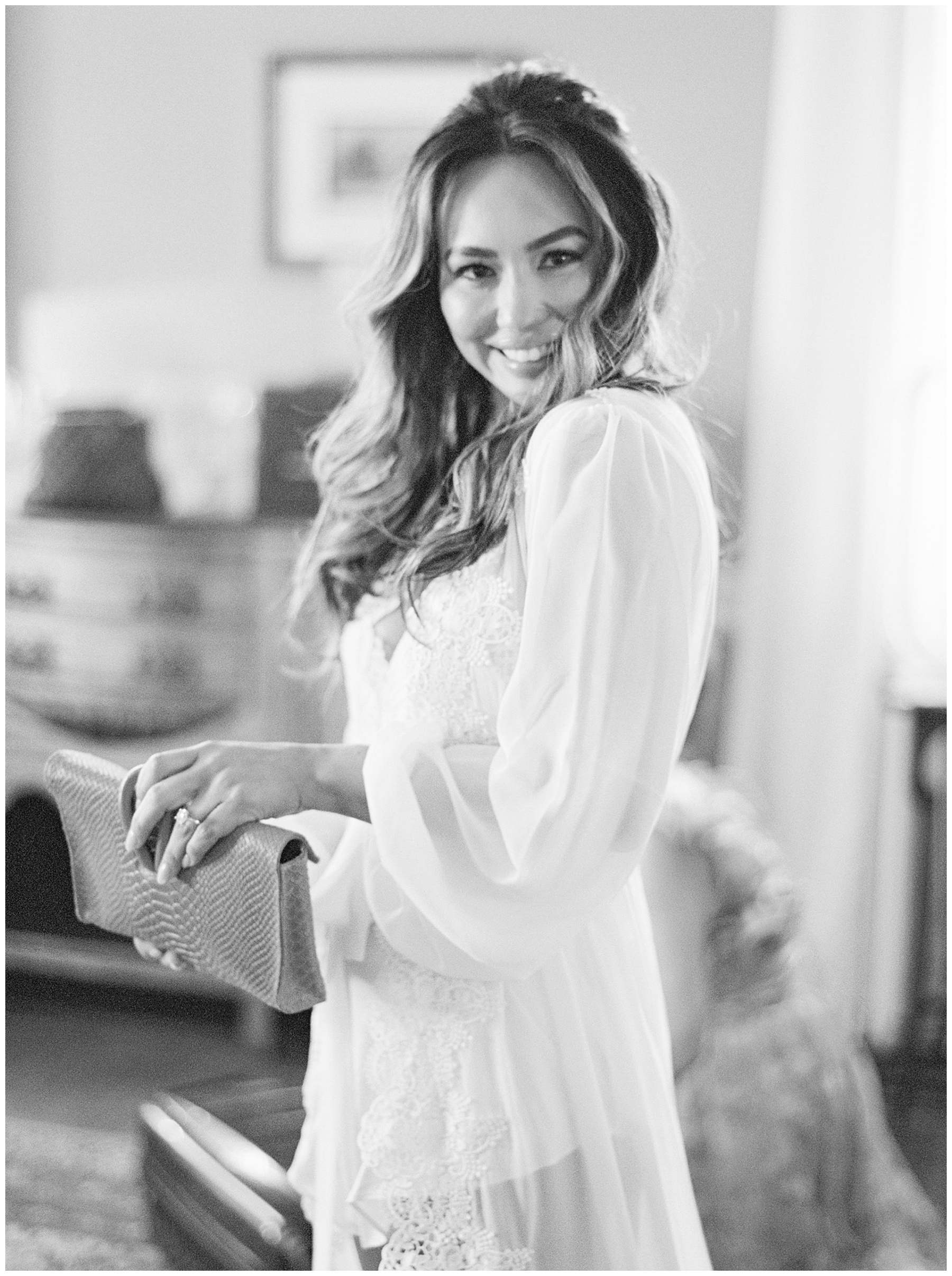 bride smiles over shoulder holding clutch on wedding morning in Charleston SC