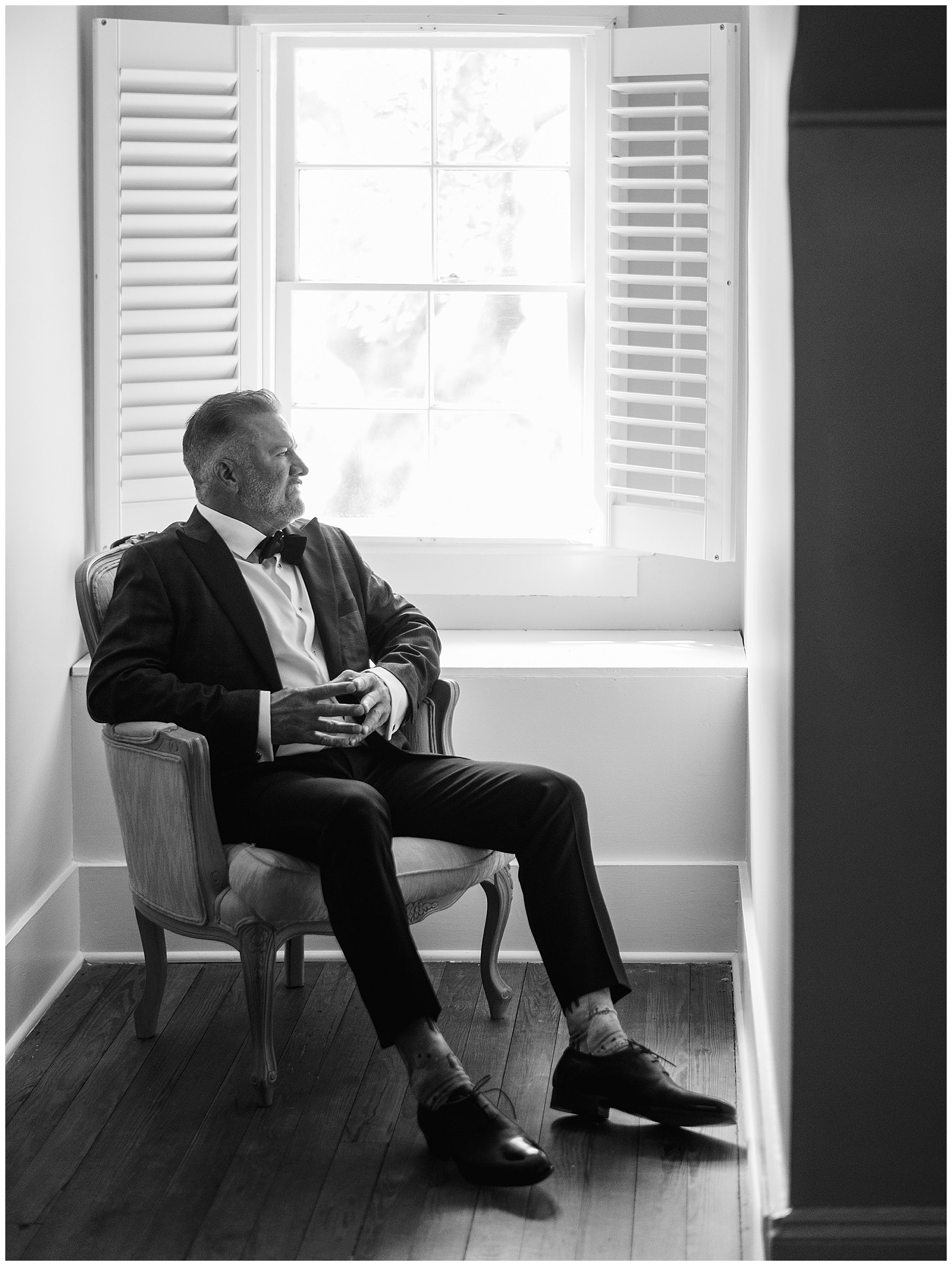 groom sits in chair looking out window at Lowndes Grove