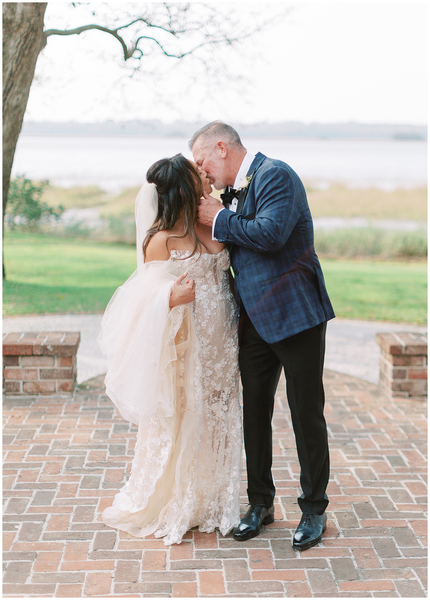 groom leans to kiss bride holding her cheek during springtime wedding day at Lowndes Grove