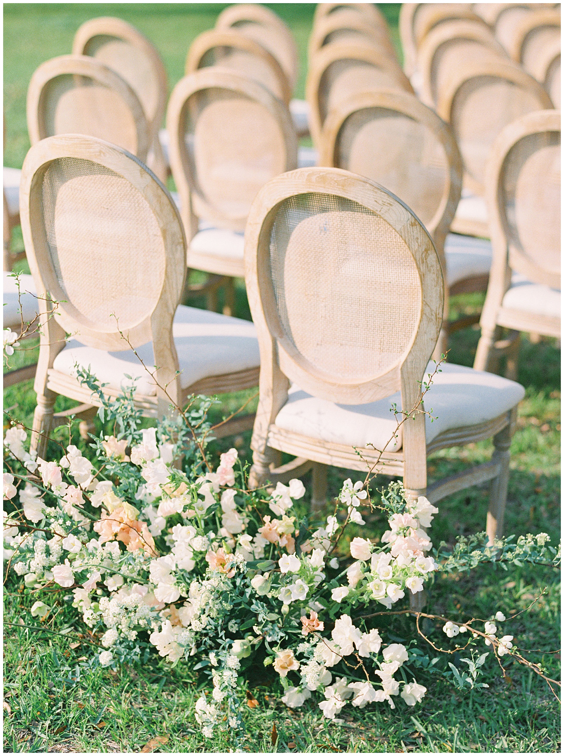 white and peach flowers sit behind row of wooden chairs for ceremony on lawn at Lowndes Grove