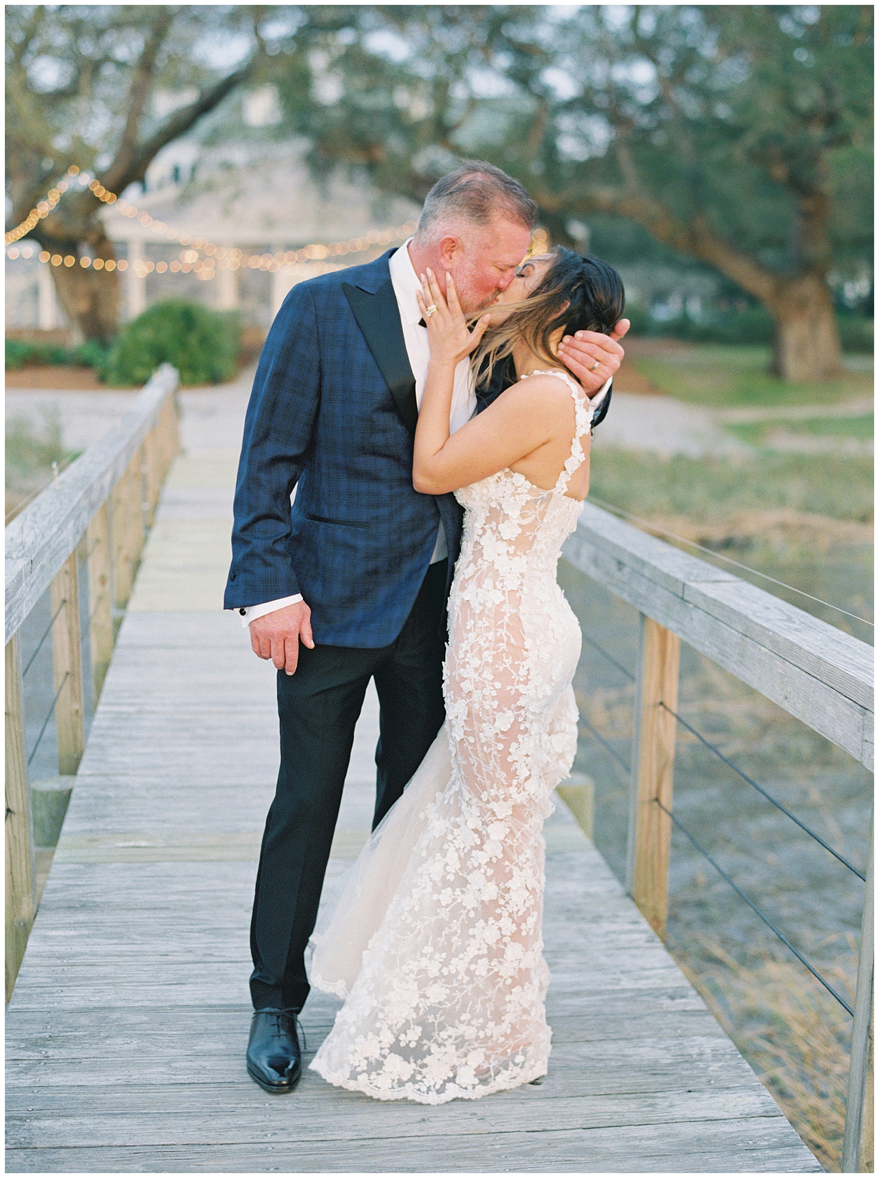 newlyweds kiss on wooden dock outside Lowndes Grove in Charleston SC