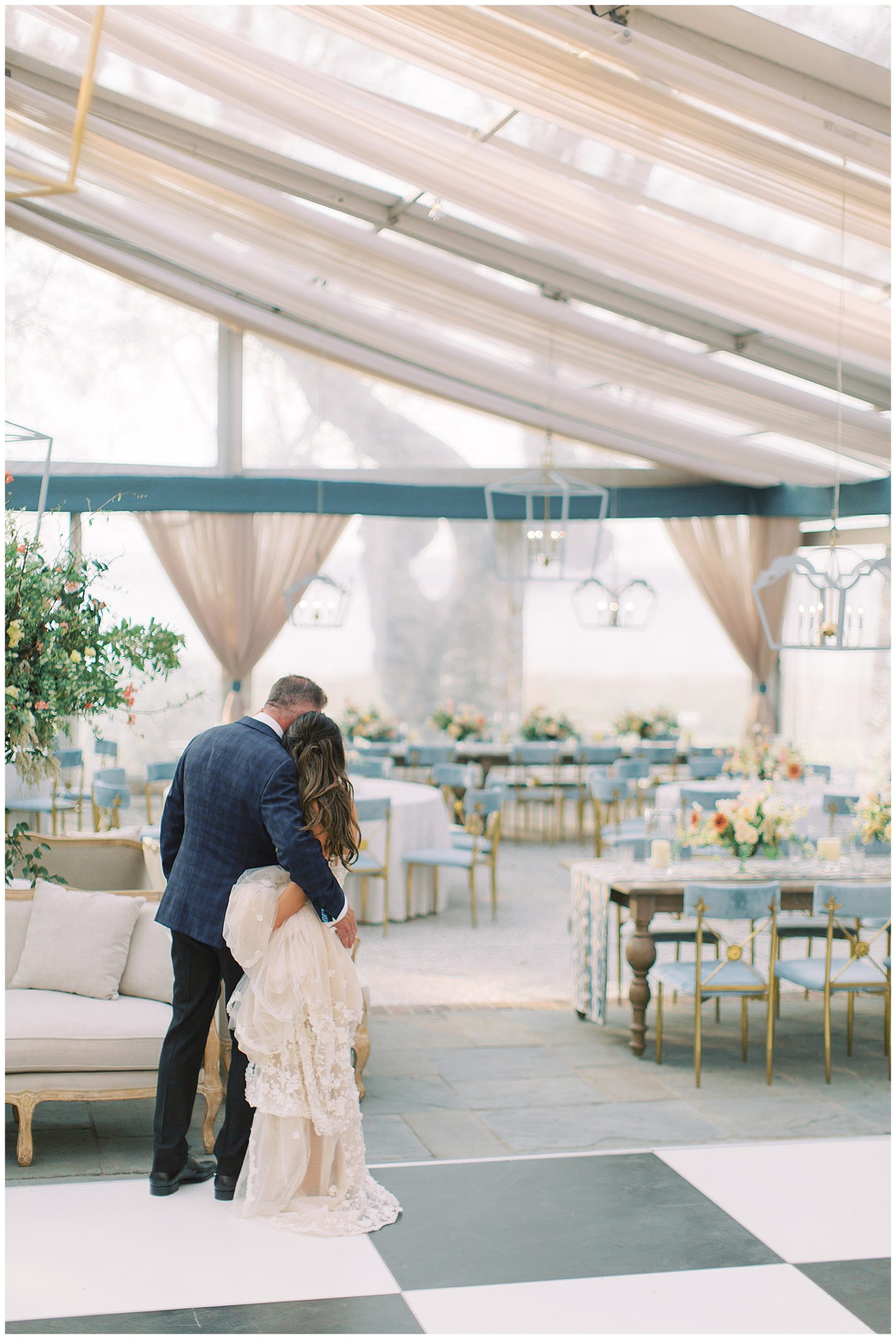 bride and groom hug near seating area under lear tent at Lowndes Grove in Charleston SC 