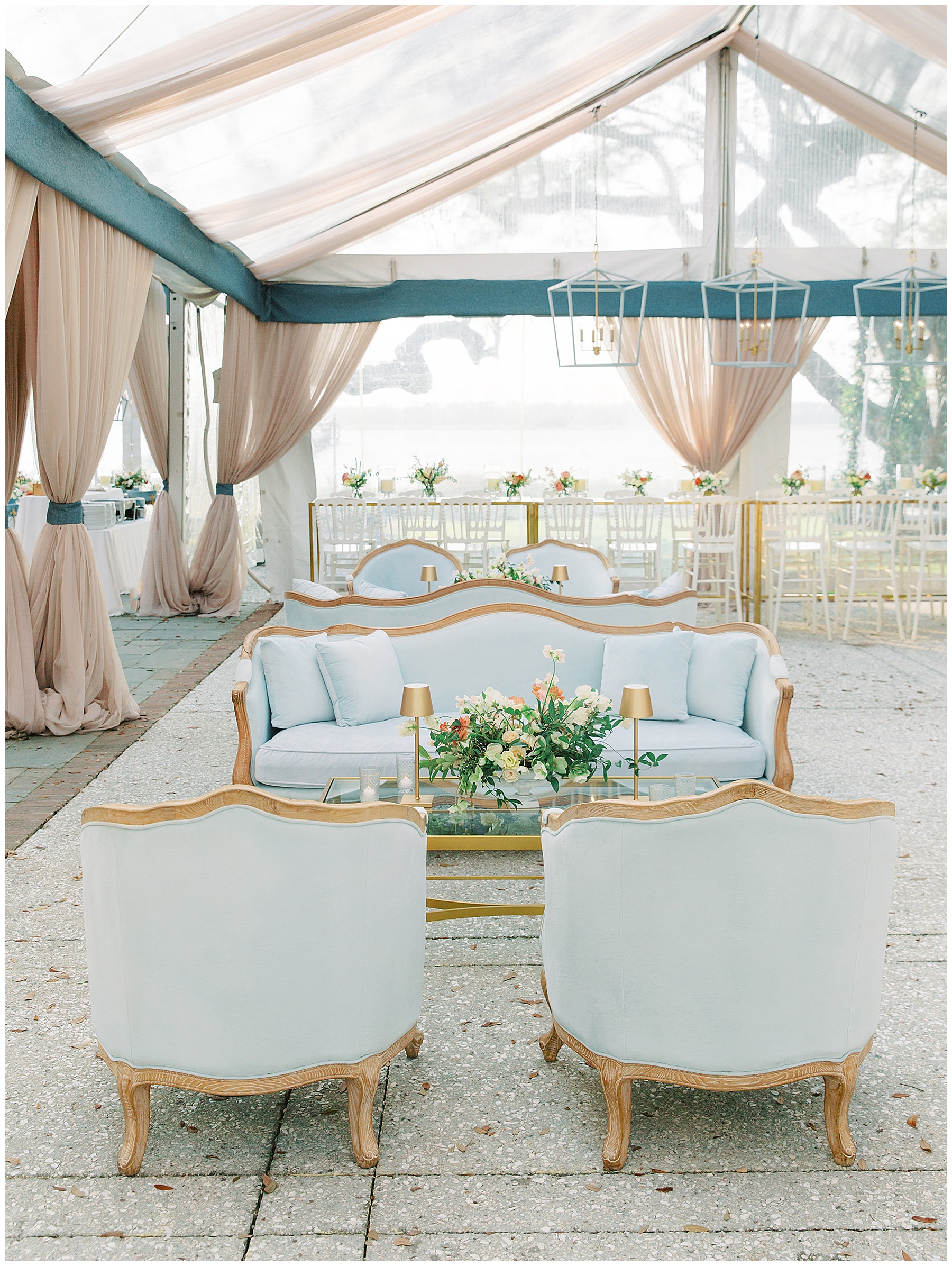 seating area under clear tent with blue and gold chairs at Lowndes Grove