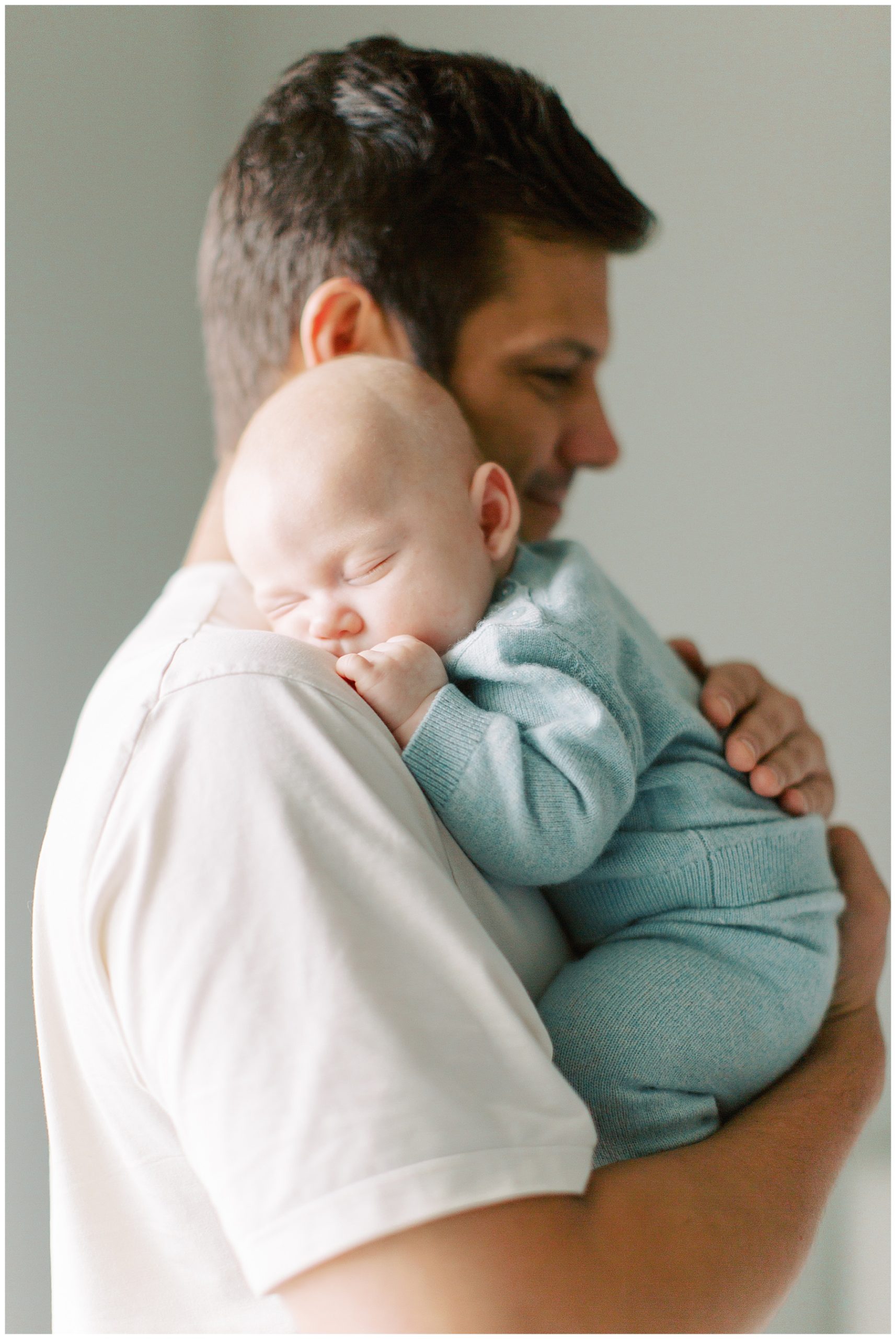 baby boy sleeps on dad's shoulder in knit outfit during Charlotte in-home newborn session