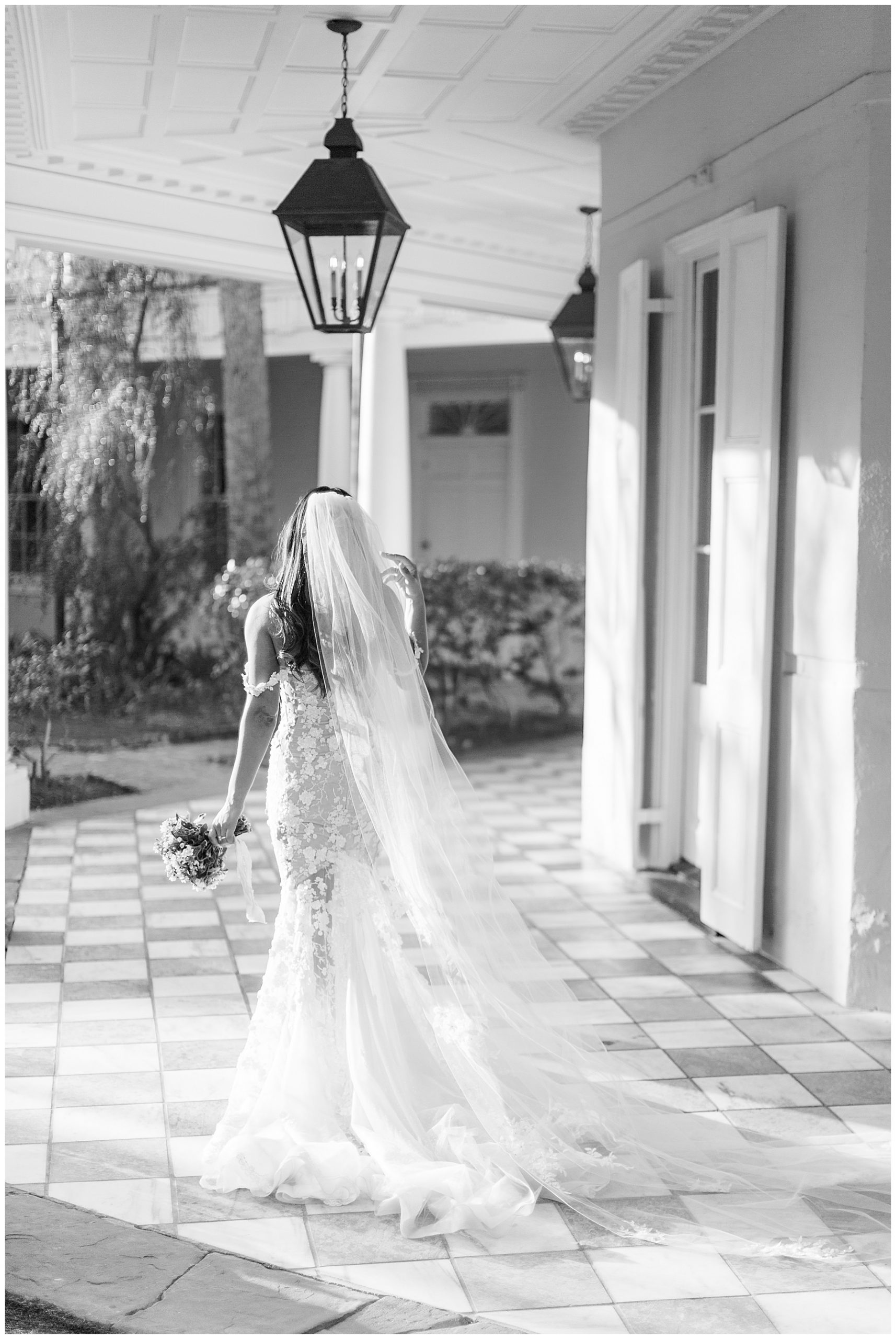 bride walks around porch outside the William Aiken House with veil trialing behind her