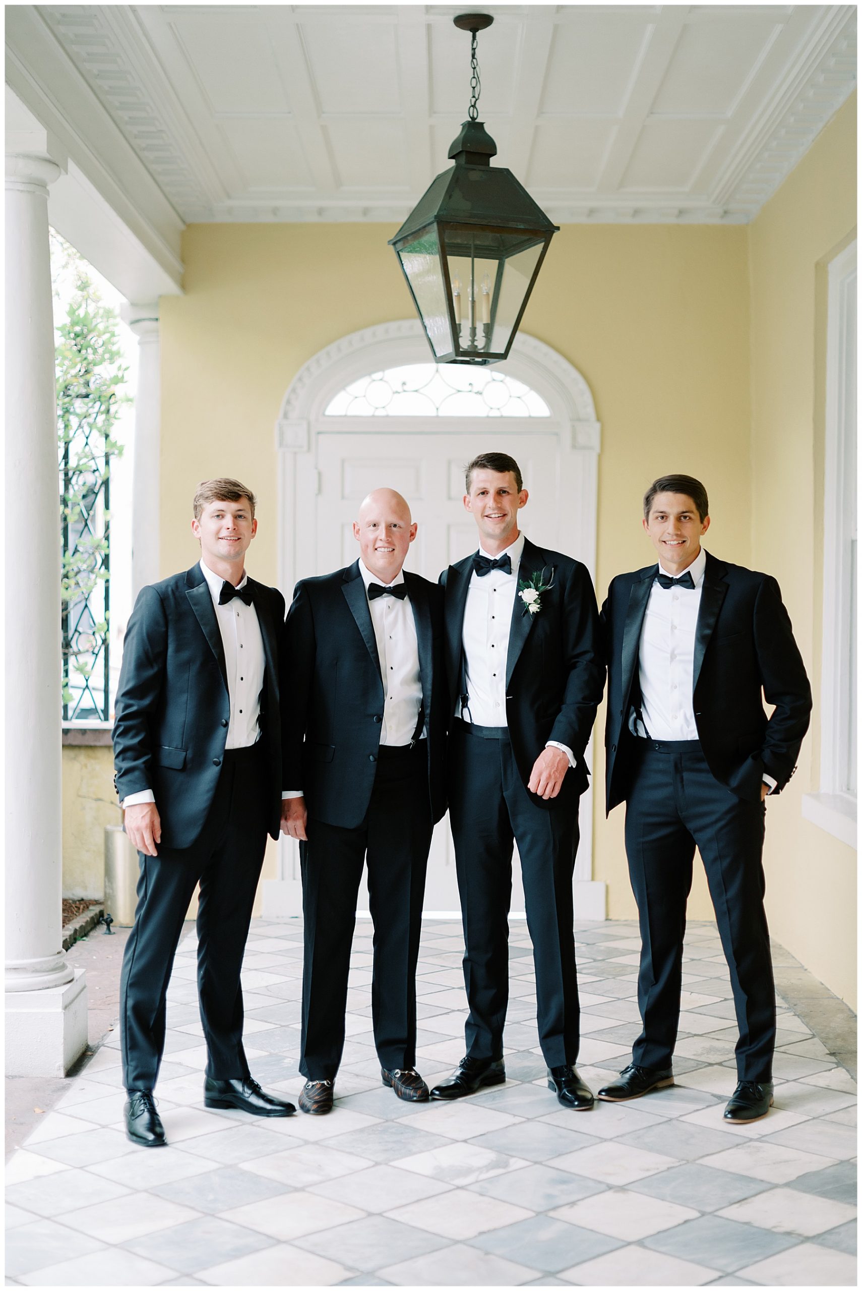 groom stand with brothers and father in front of yellow walls at the William Aiken House