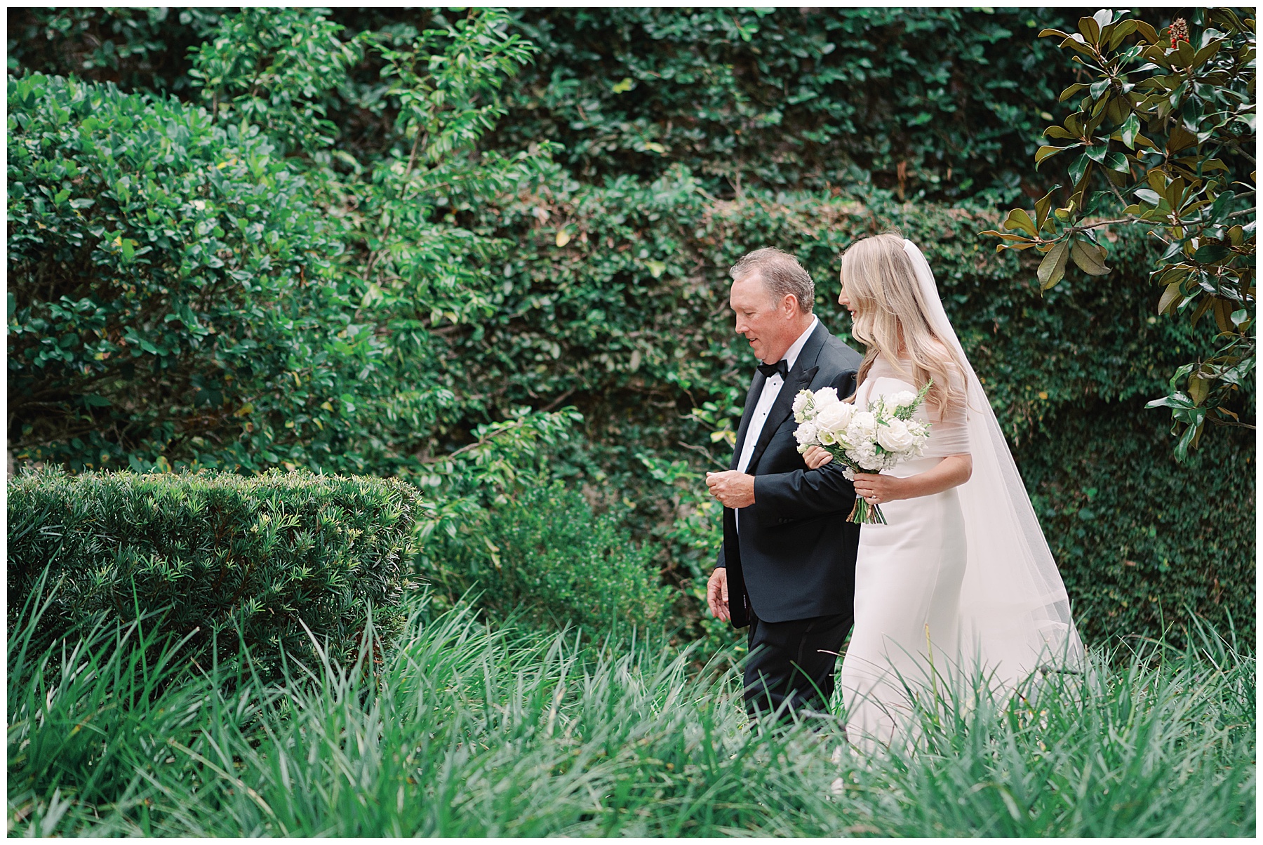 father walks with bride through hedges at the William Aiken House