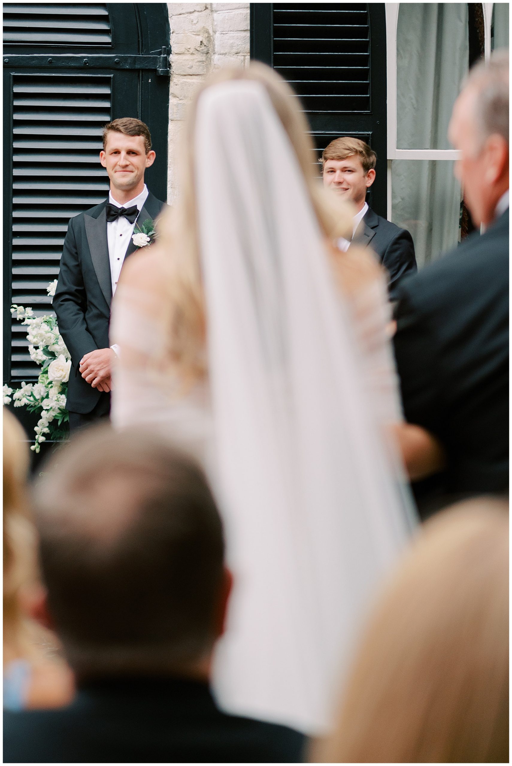 groom grins at bride watching her walk down the aisle at the William Aiken House