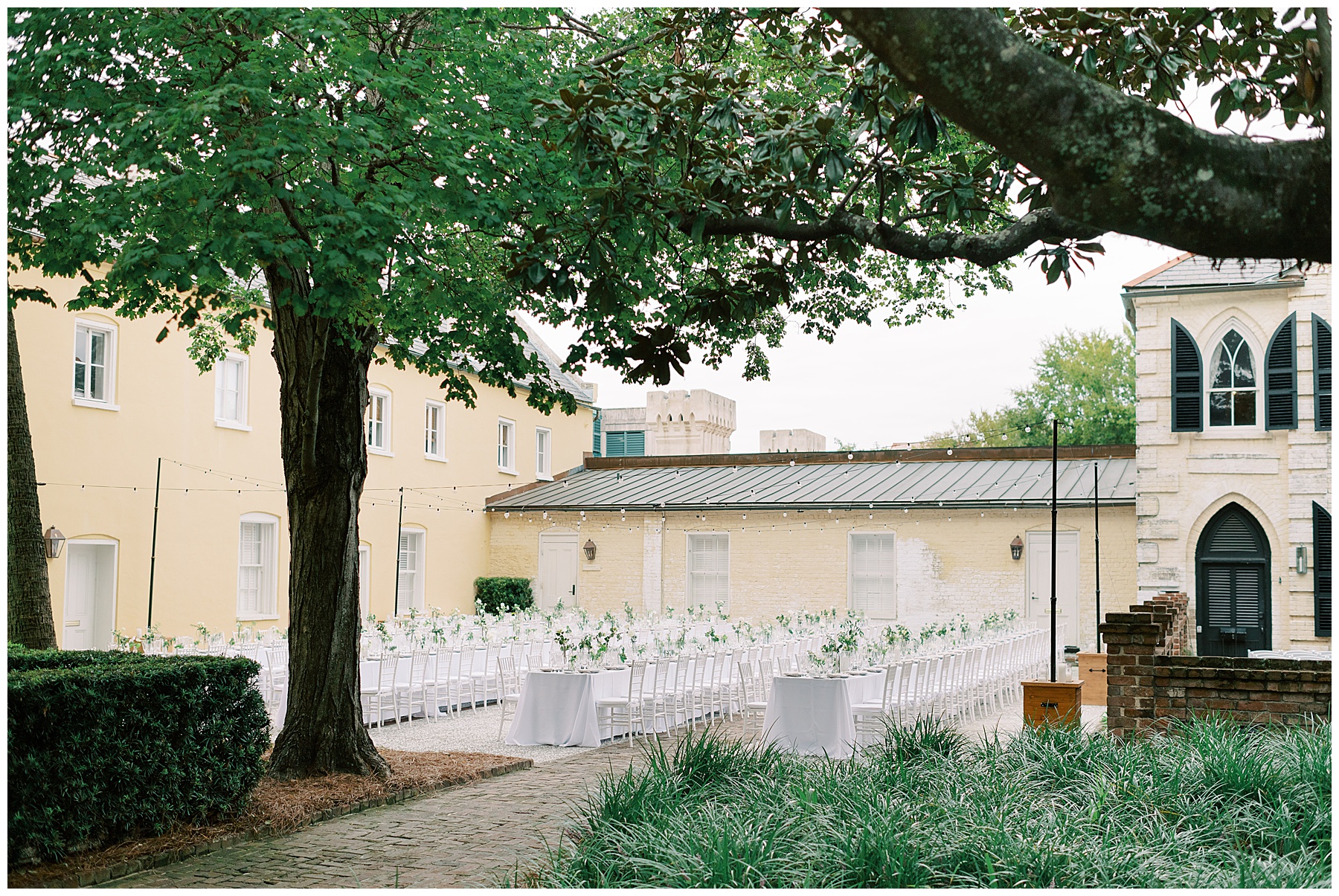 al fresco wedding reception on patio with white table clothes, chairs and white flowers down the middle 
