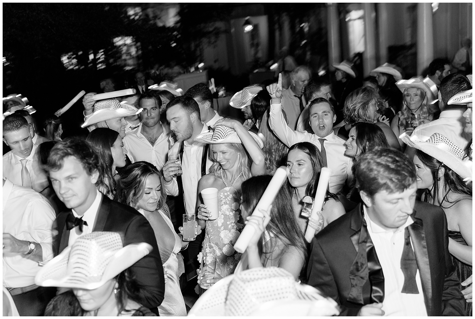 wedding guests dance in cowboy hats with glow sticks on dance floor at the William Aiken House