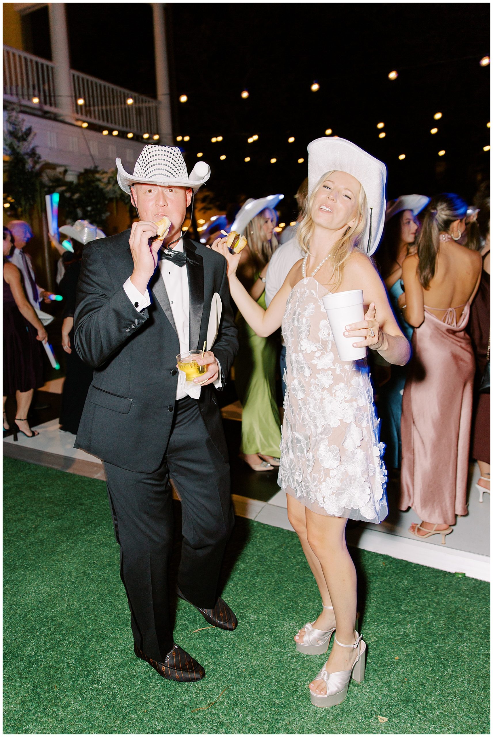 bride and groom pose in white cowboy hats near dance floor in Charleston SC