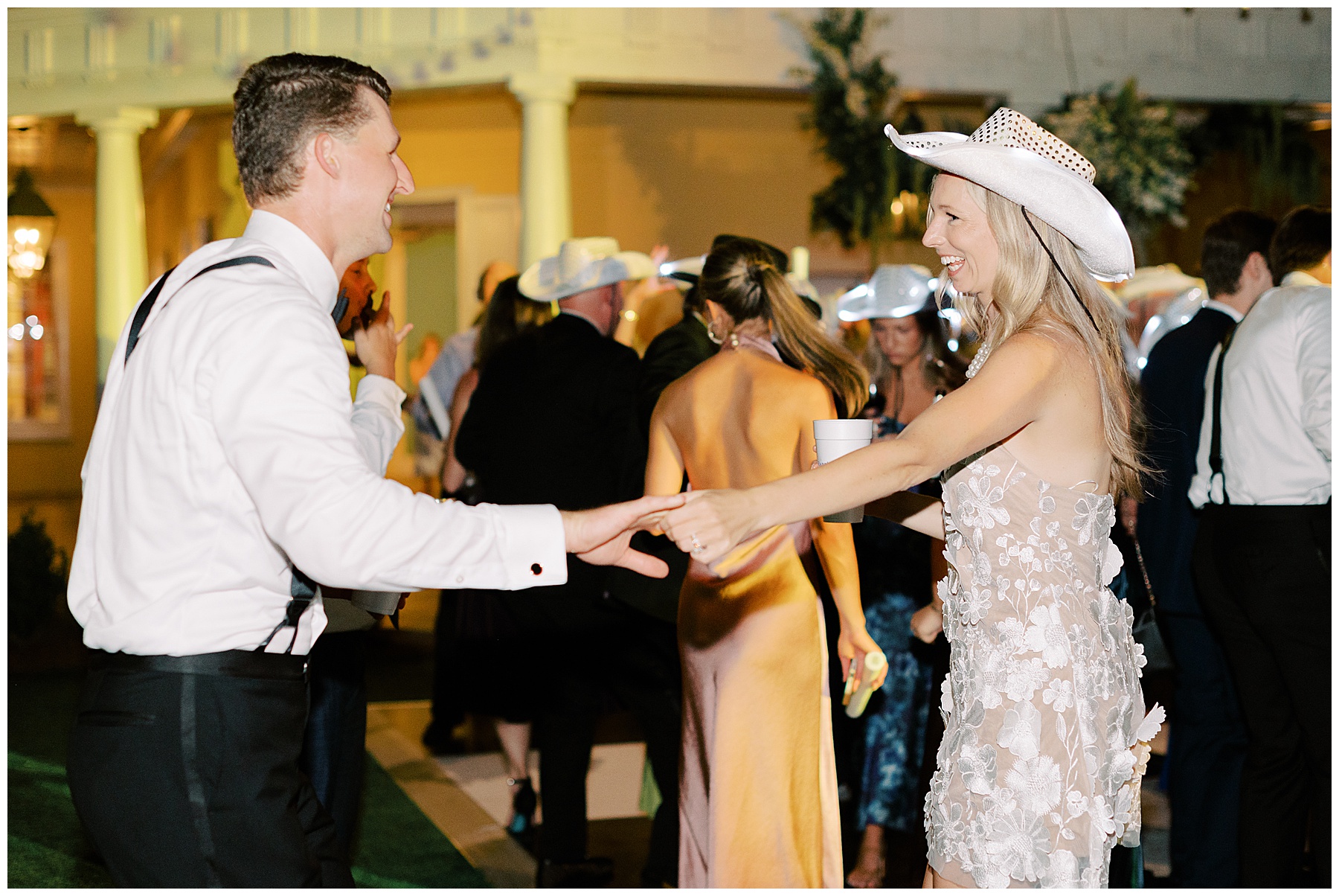 groom dances with bride in fun reception dress and white cowgirl hat on dance floor at the William Aiken House