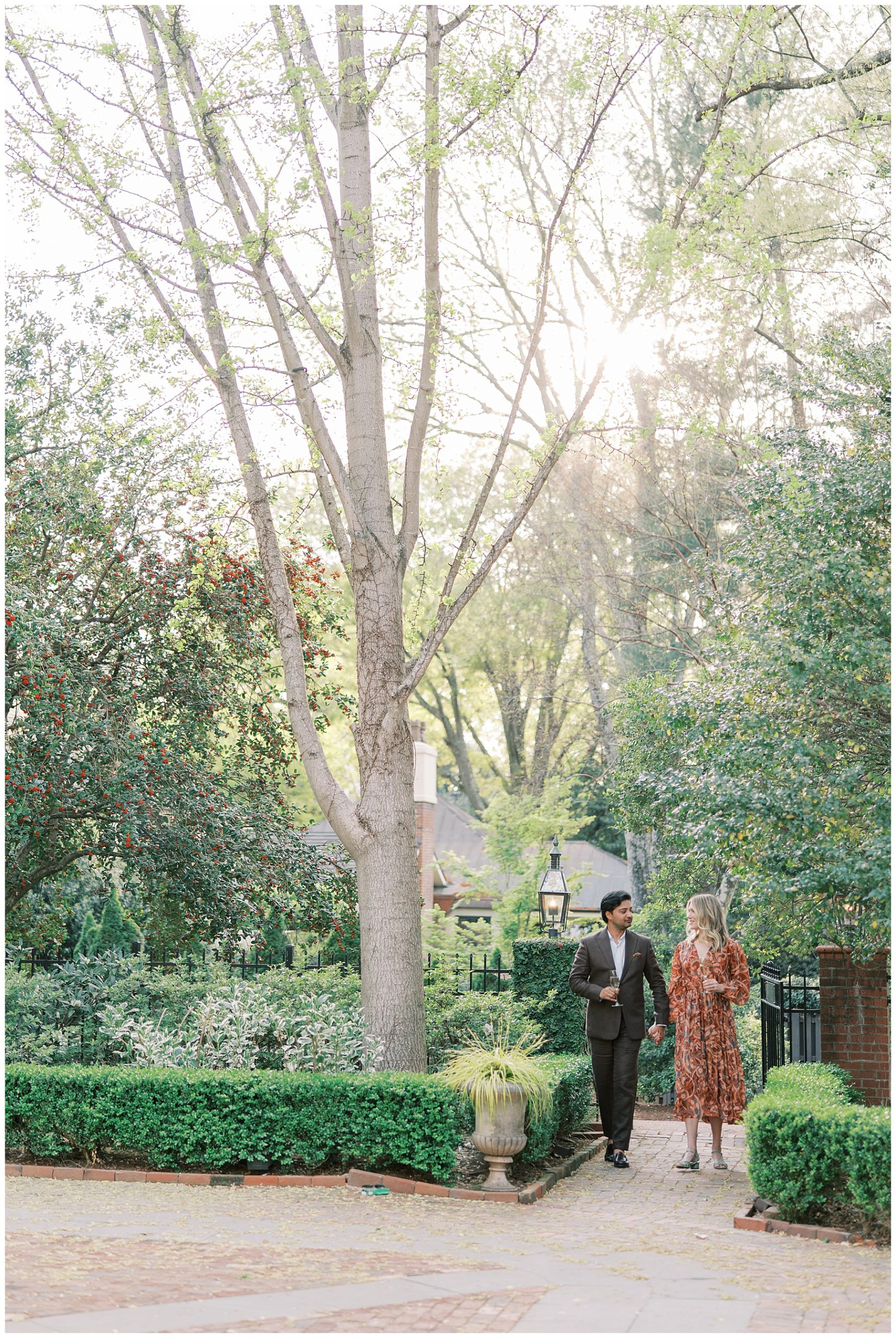 man and woman hold hands walking into gardens of Duke Mansion in North Carolina