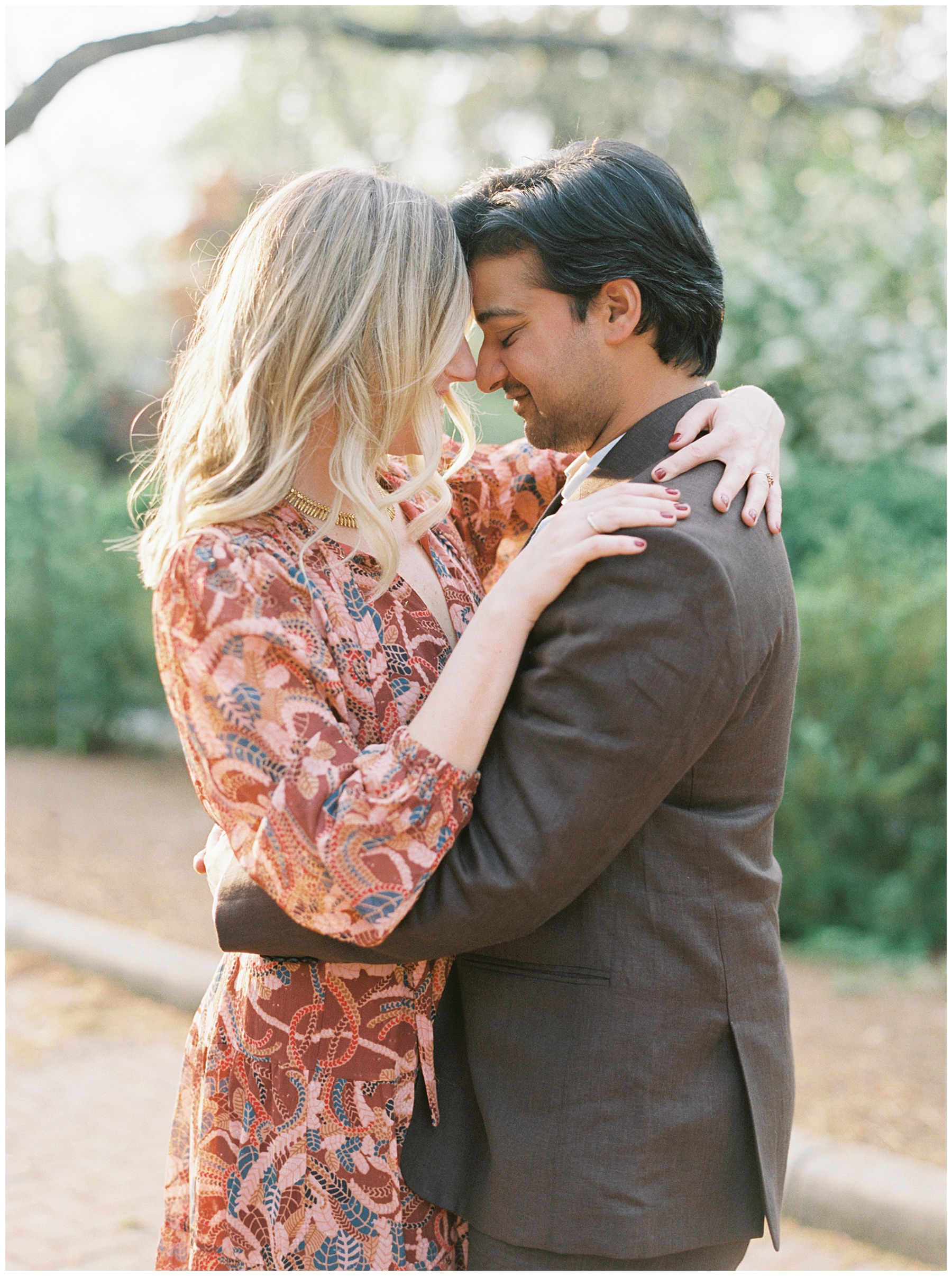 engaged couple hugs leaning heads together with arms around their shoulders during Duke Mansion engagement session