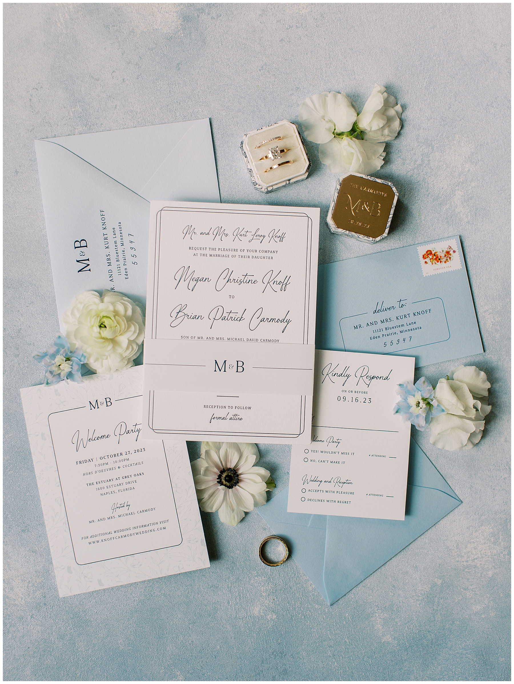 blue and white invention suite with ring box and white flowers around outside 