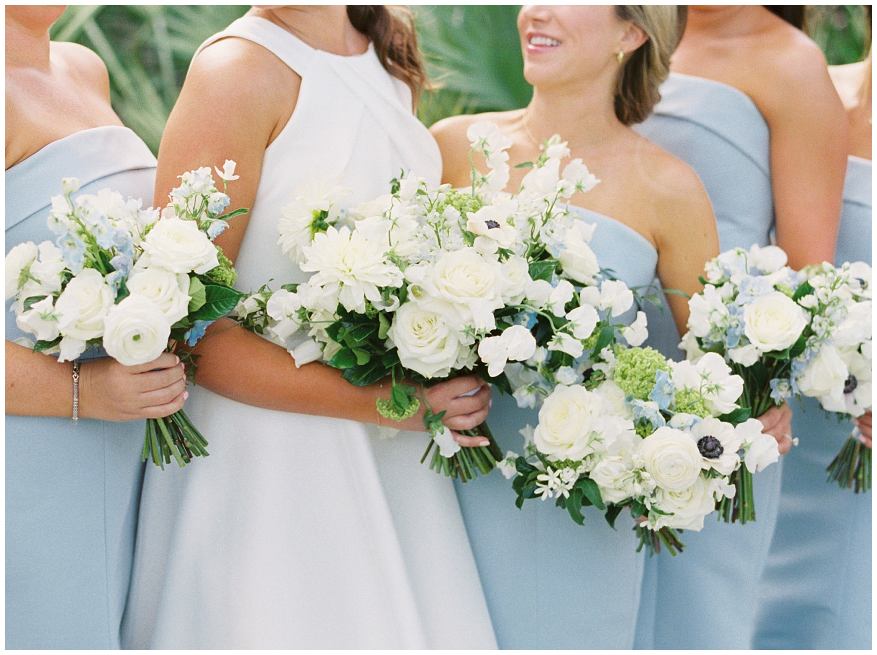 film photo of bride holding blue and white bouquet with bridesmaids in blue gowns