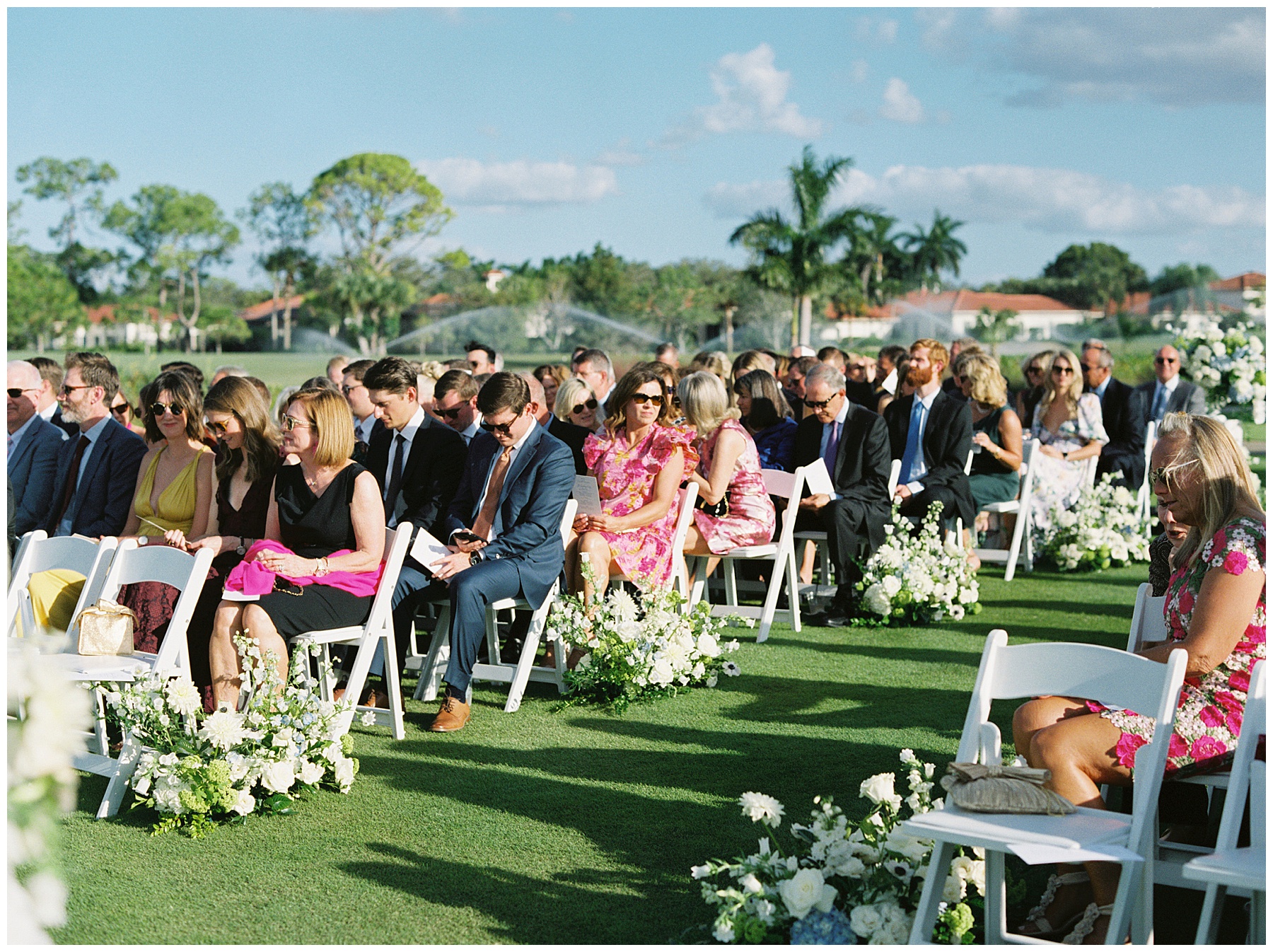 wedding guests sit on green at Grey Oaks Country Club waiting for ceremony 