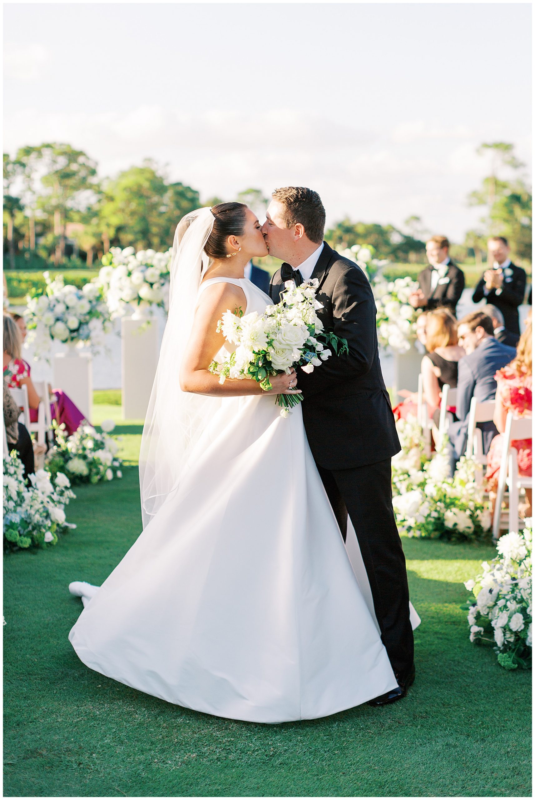 newlyweds kiss in aisle after ceremony on lawn at Grey Oaks Country Club