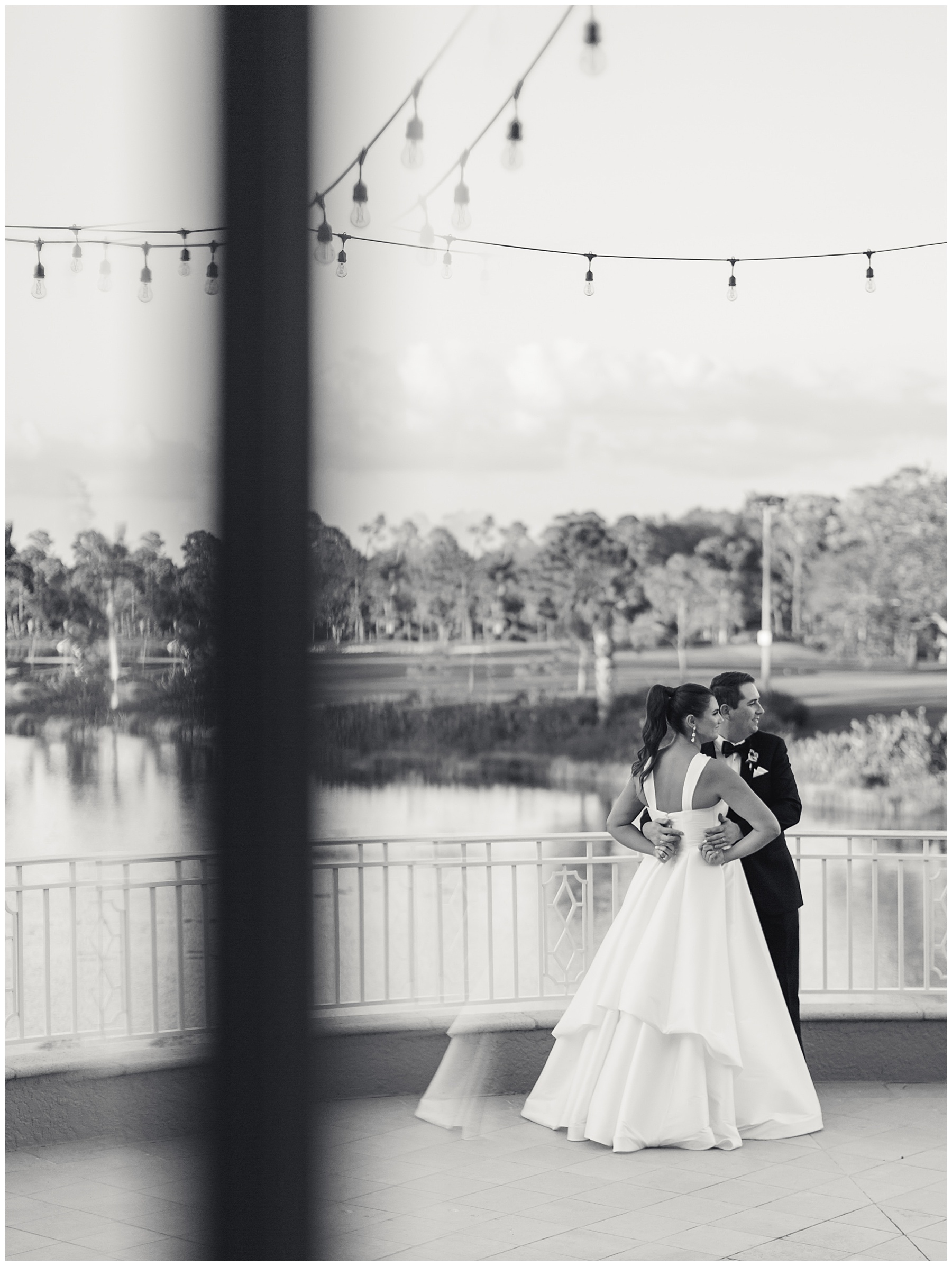 black and white photo on patio at Grey Oaks Country Club of bride and groom hugging