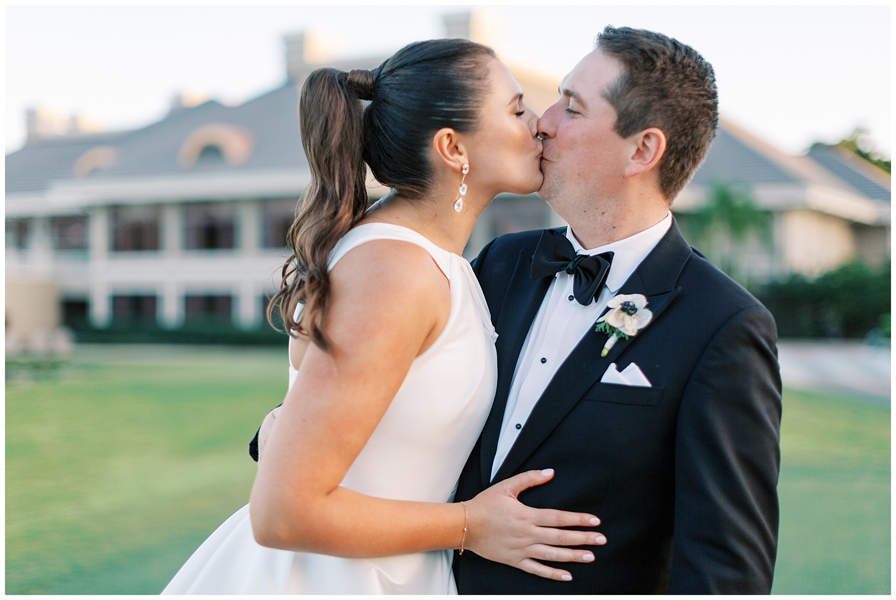 bride and groom kiss on lawn at Grey Oaks Country Club