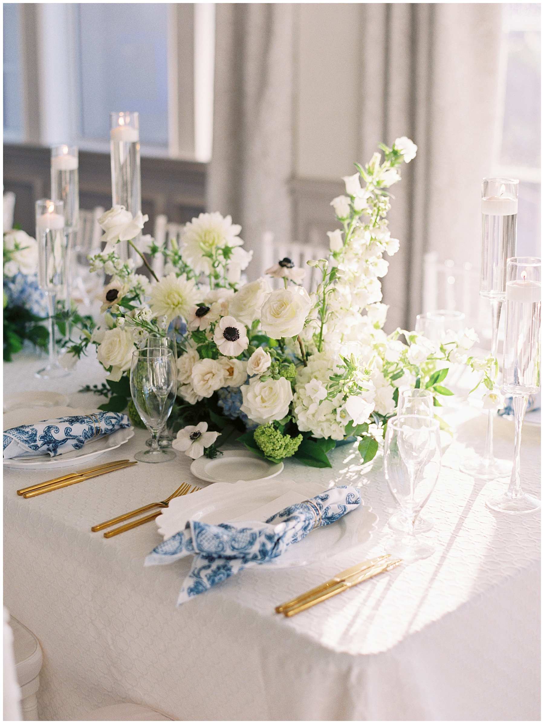 place setting with blue and white napkins, gold silverware, and white floral centerpiece at Grey Oaks Country Club