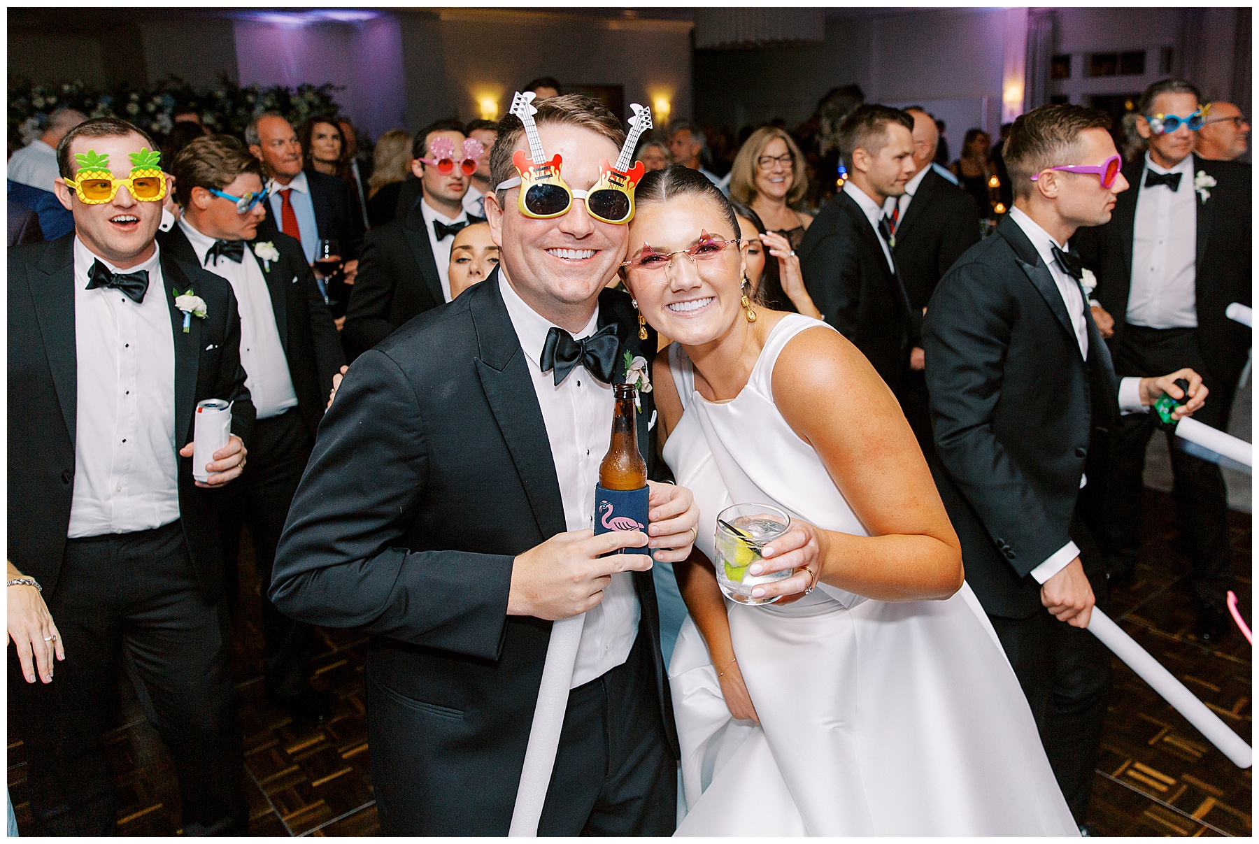 bride and groom pose on dance floor with funny sunglasses and drinks at Grey Oaks Country Club