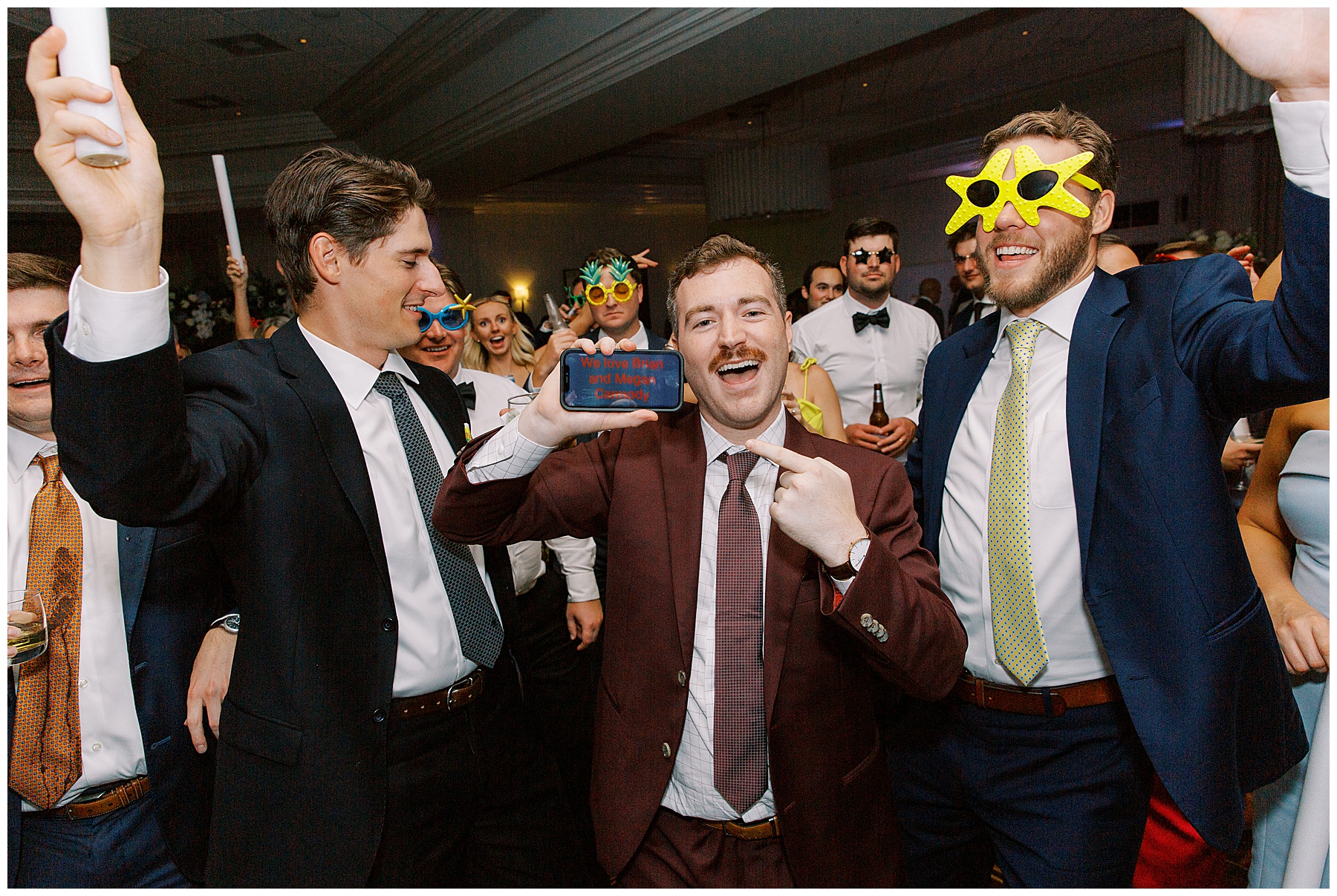 wedding guest holds up phone that says "We love Brian and Megan"