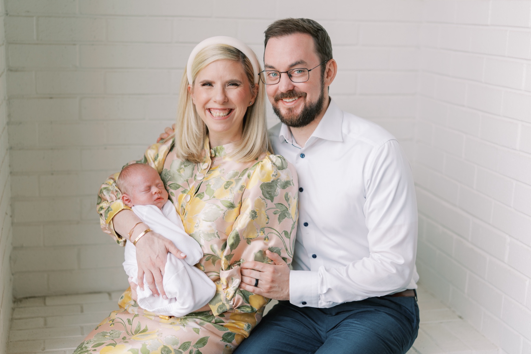 parents cradle their baby daughter seated in a brick nook of their residence in Charlotte NC