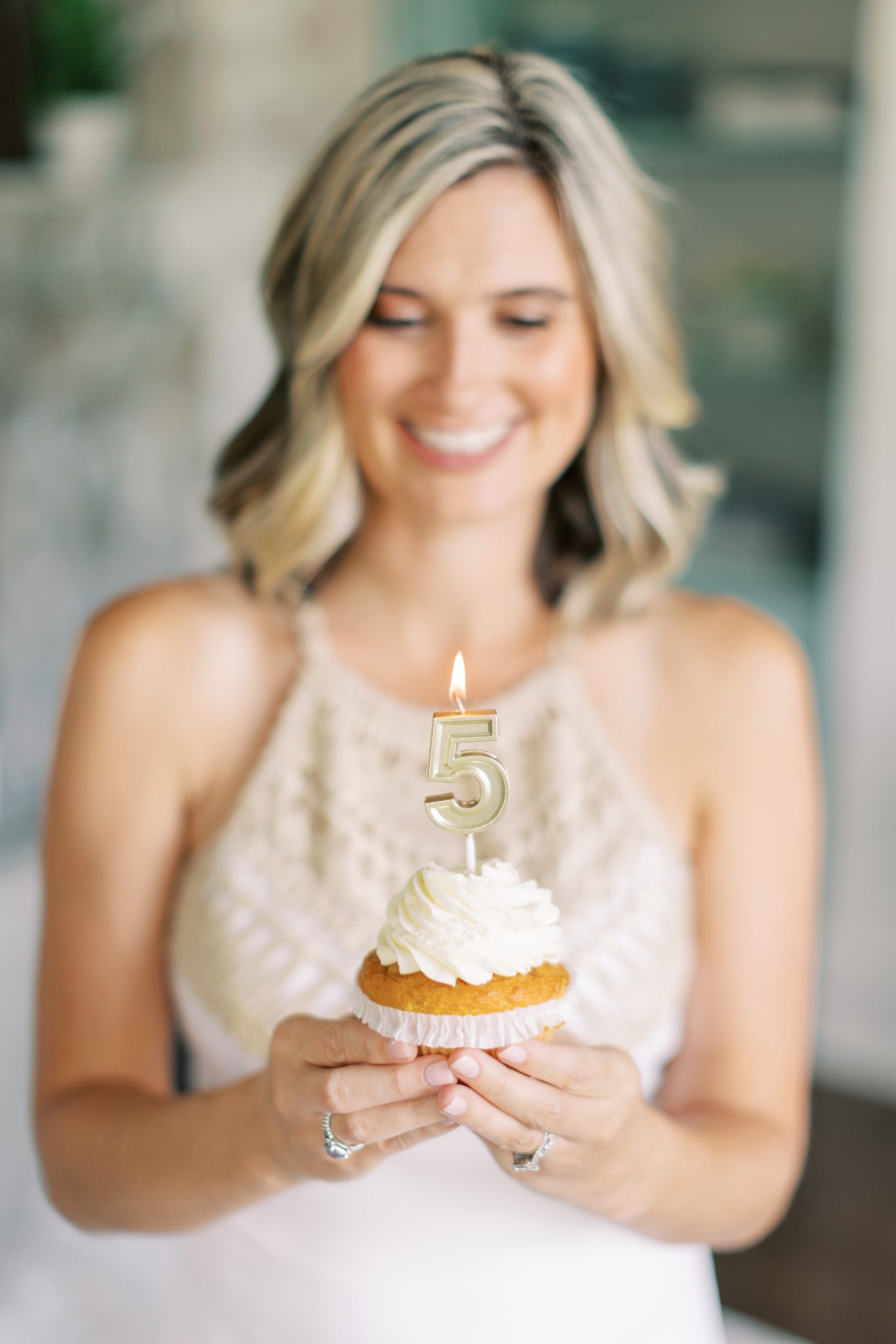 blonde woman holds cupcake with gold 5 candle on top during Charlotte branding photos
