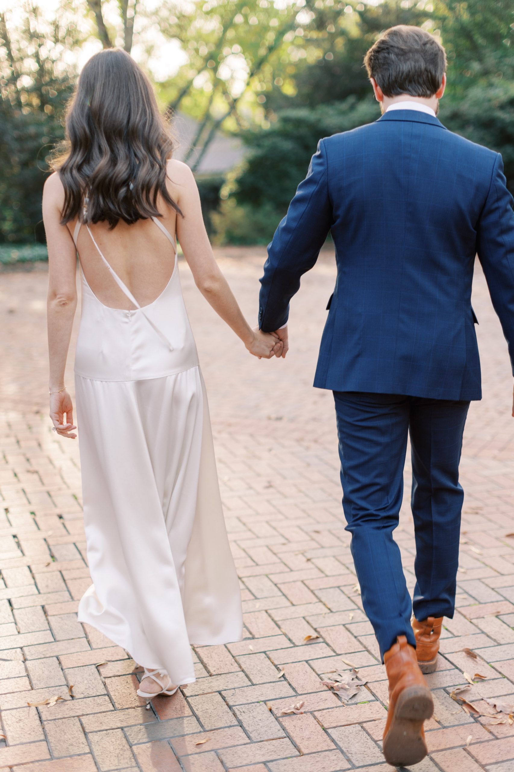 engaged couple holds hands walking on brick patio in Charlotte NC