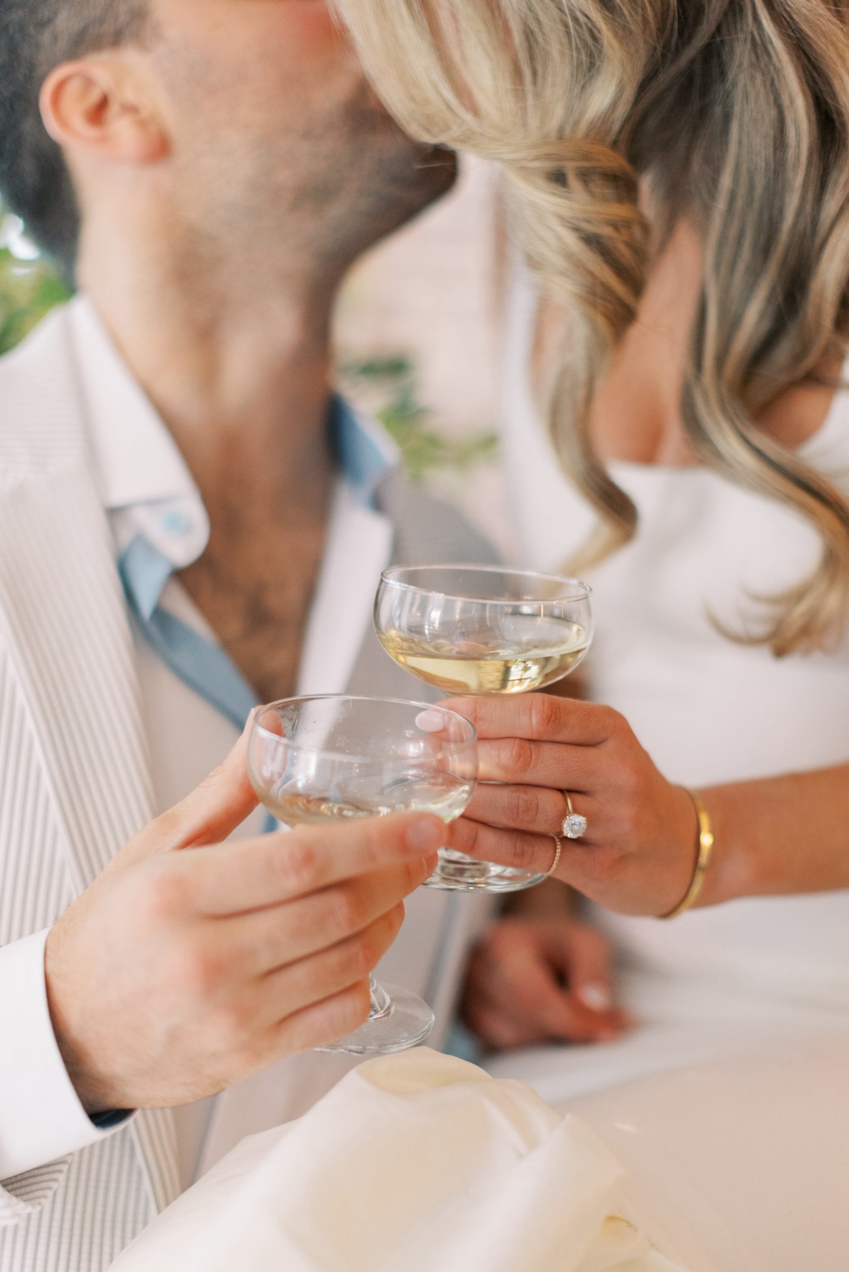 bride and groom kiss holding glasses of champagne