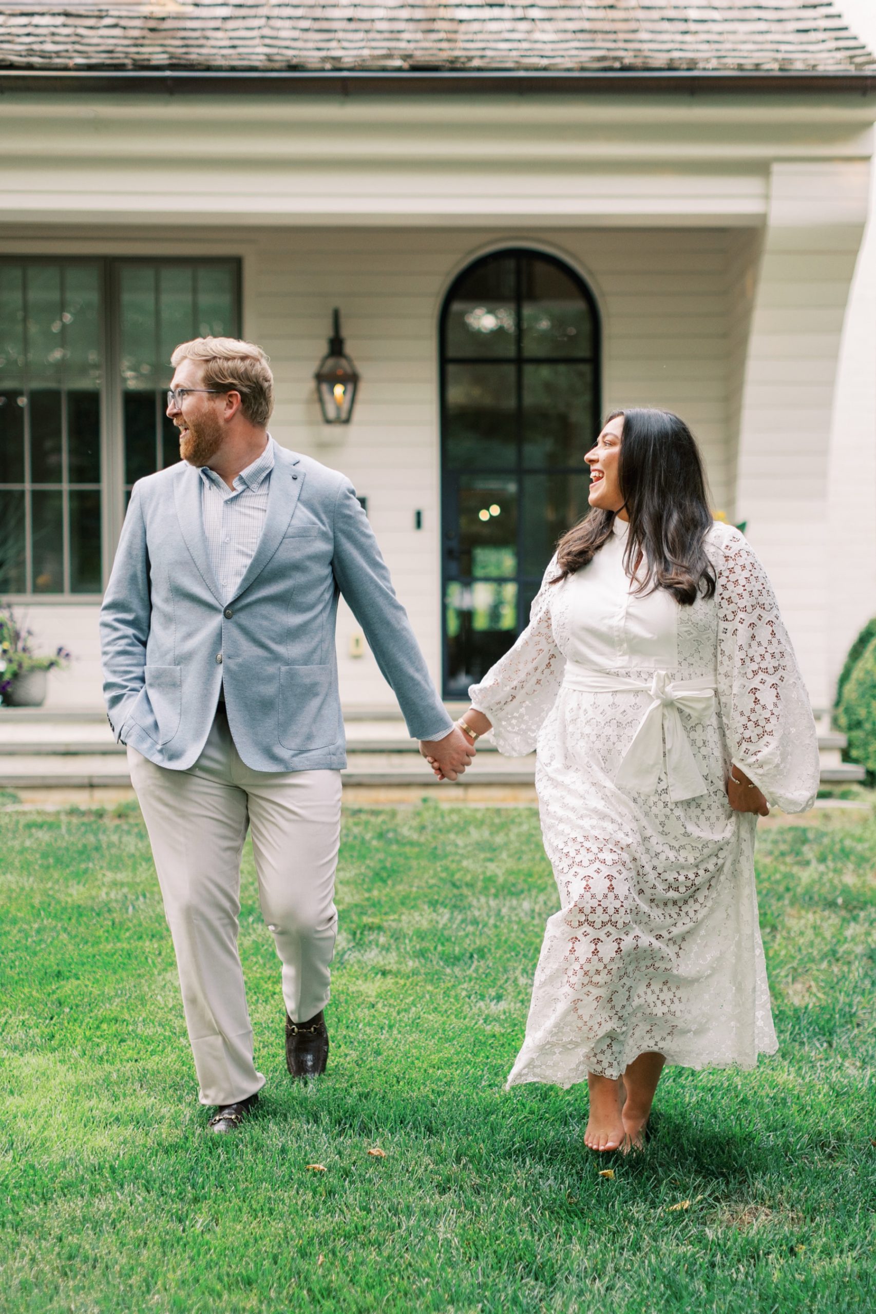 Couple hold hands and walk across lawn 