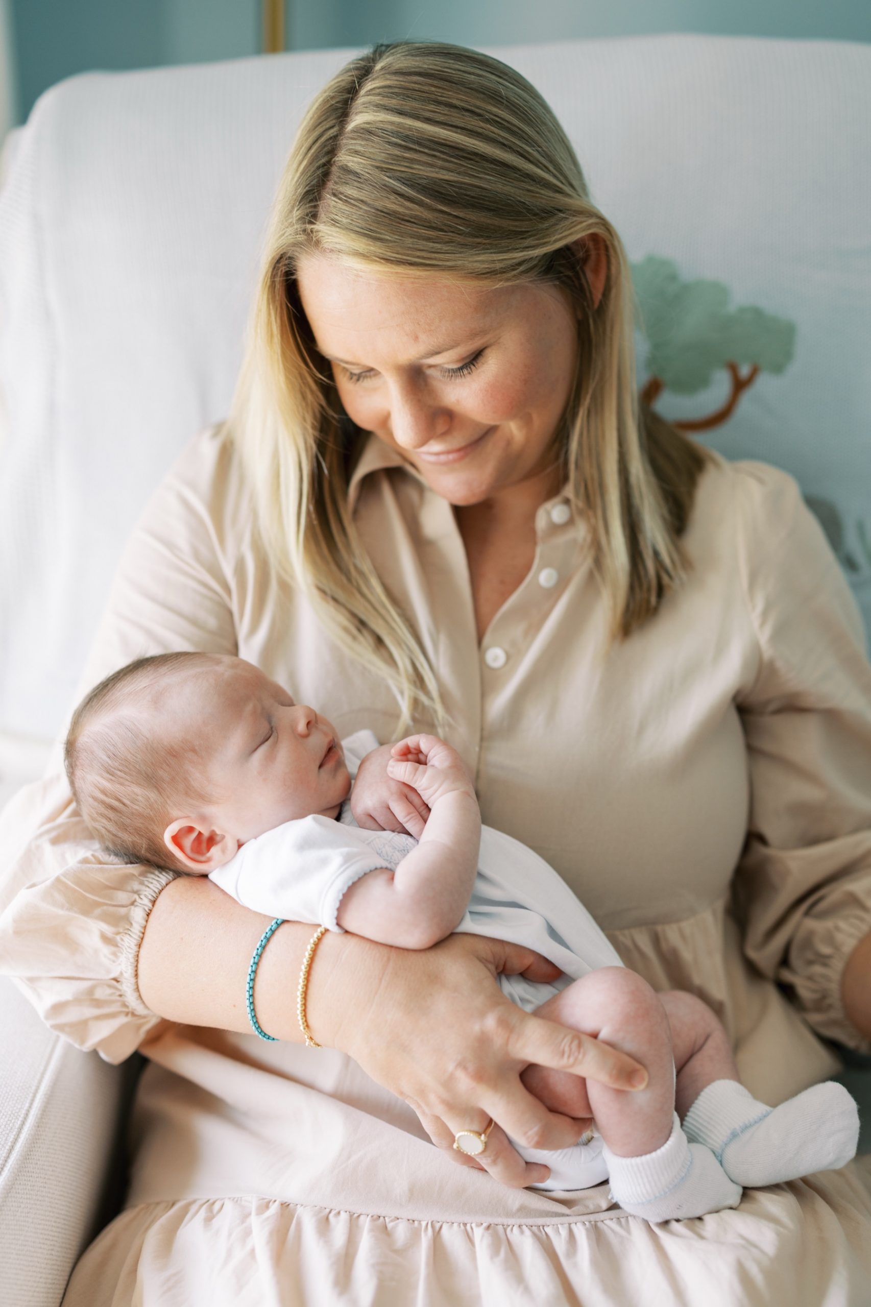 mom holds sleeping newborn during in-home lifestyle session