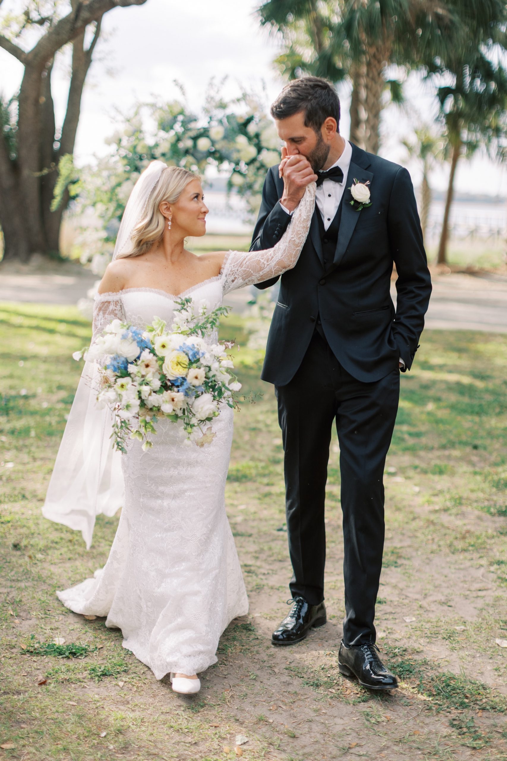 groom kisses bride's hand as they walk together 