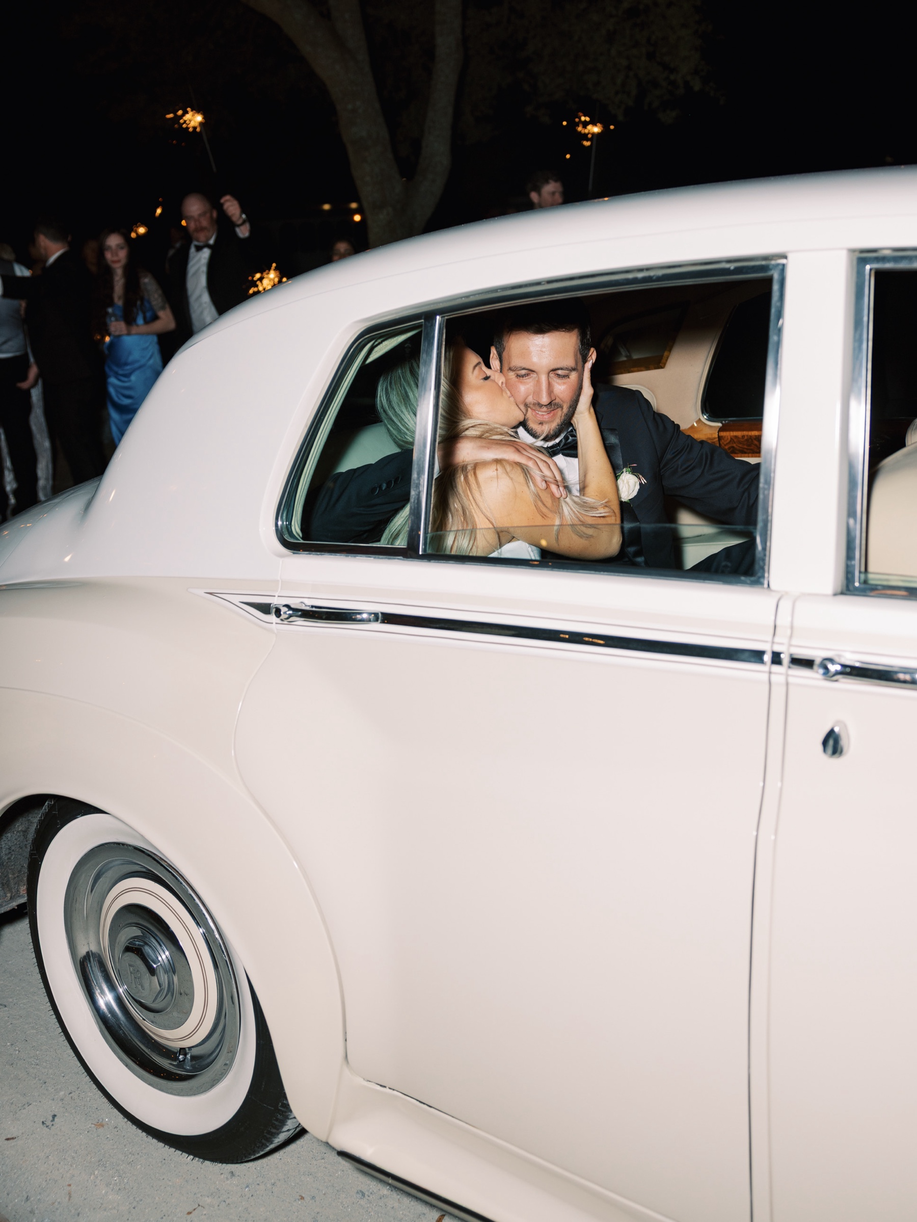 bride kisses groom's cheek in back of car
