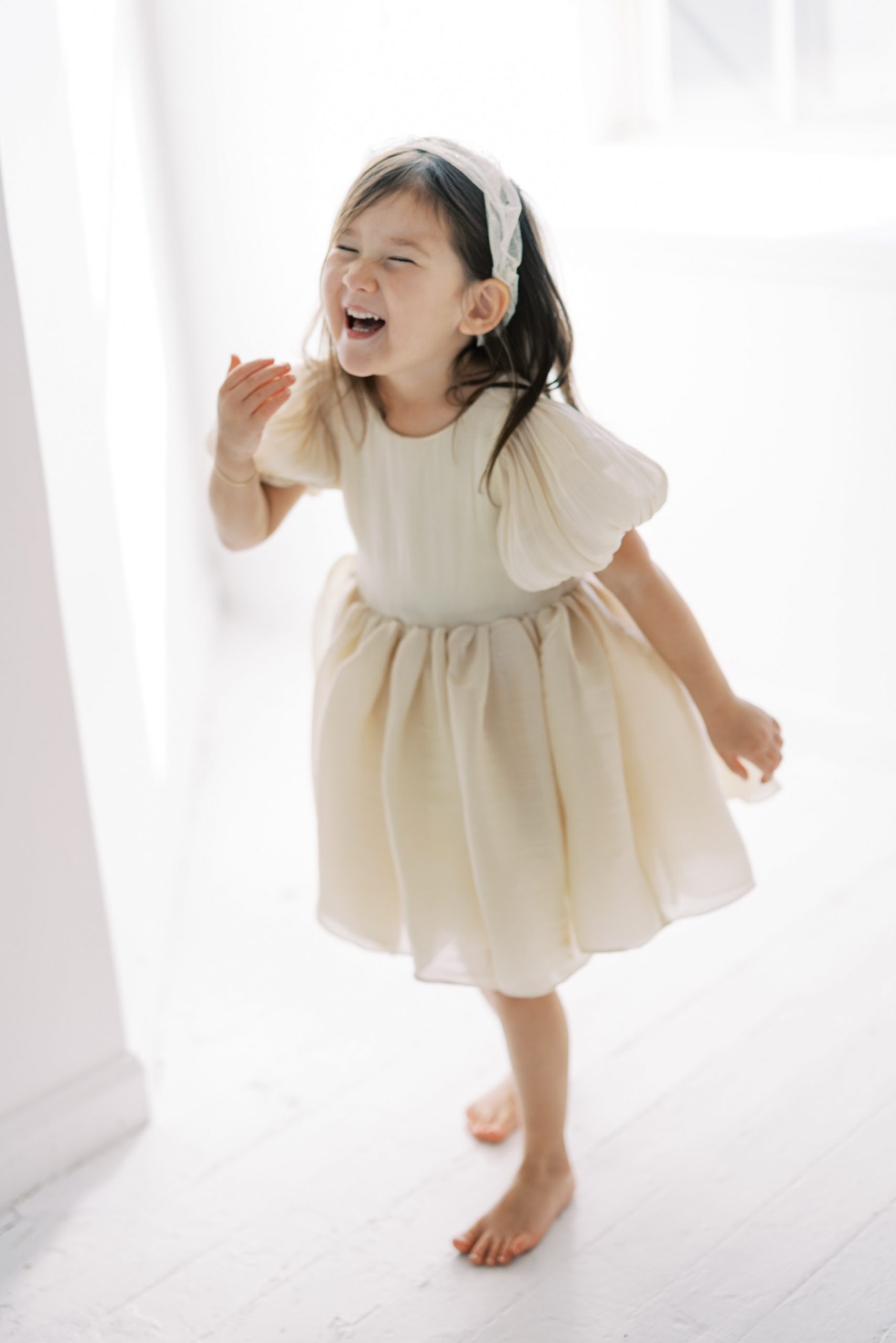 little girl in dress laughs during sweet mother daughter session 