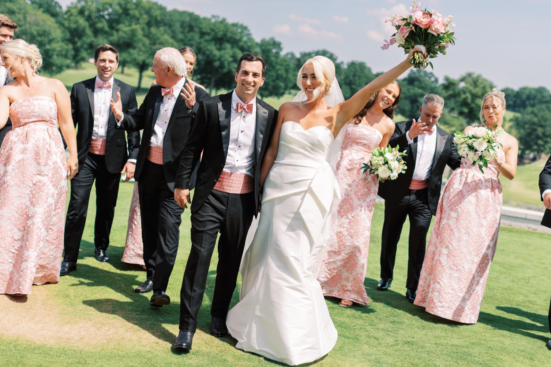wedding party in pink themed attire surround newlyweds
