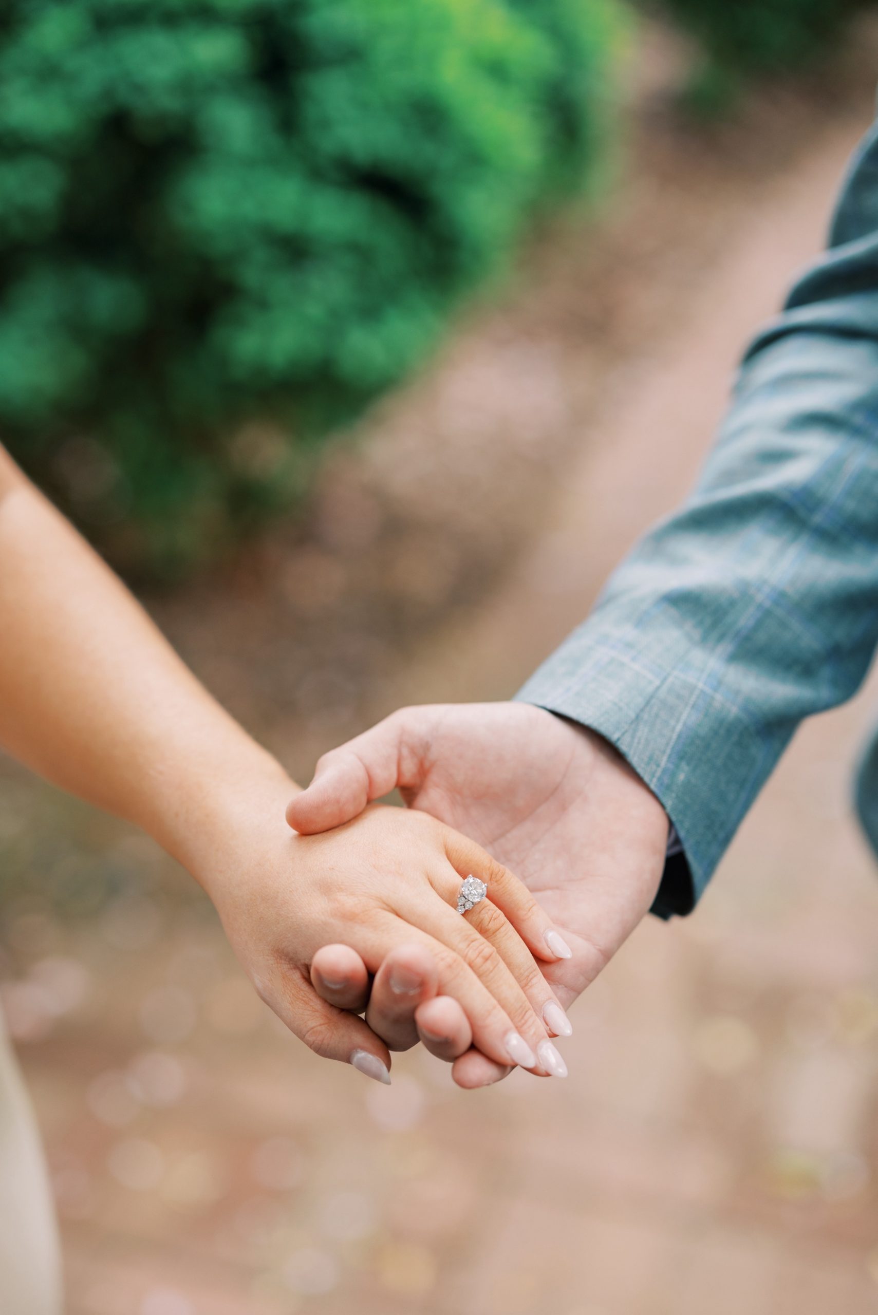 couple hold hands and show off engagement ring