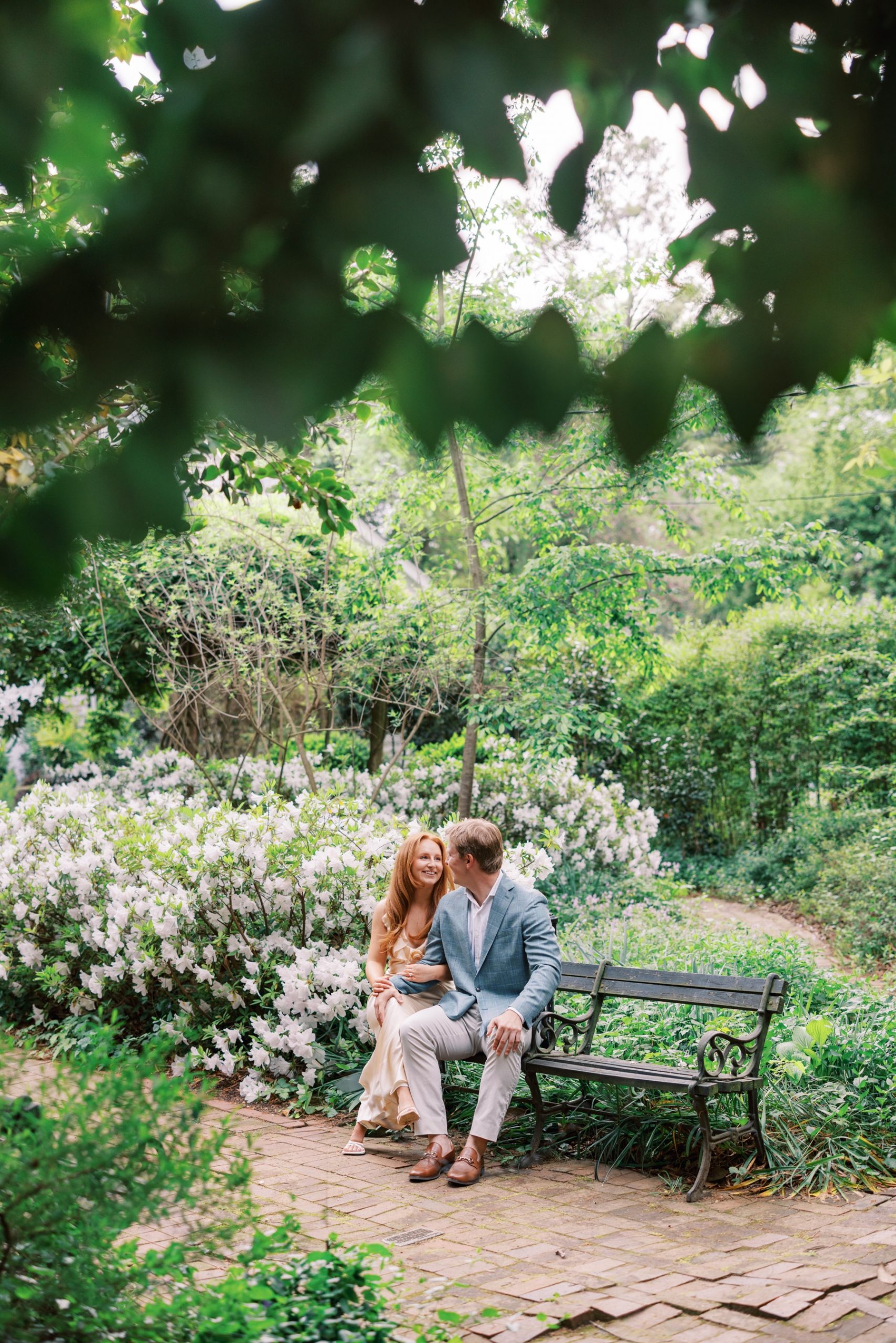 couple sit on bench at Wing Haven Gardens surrounded by spring blooms