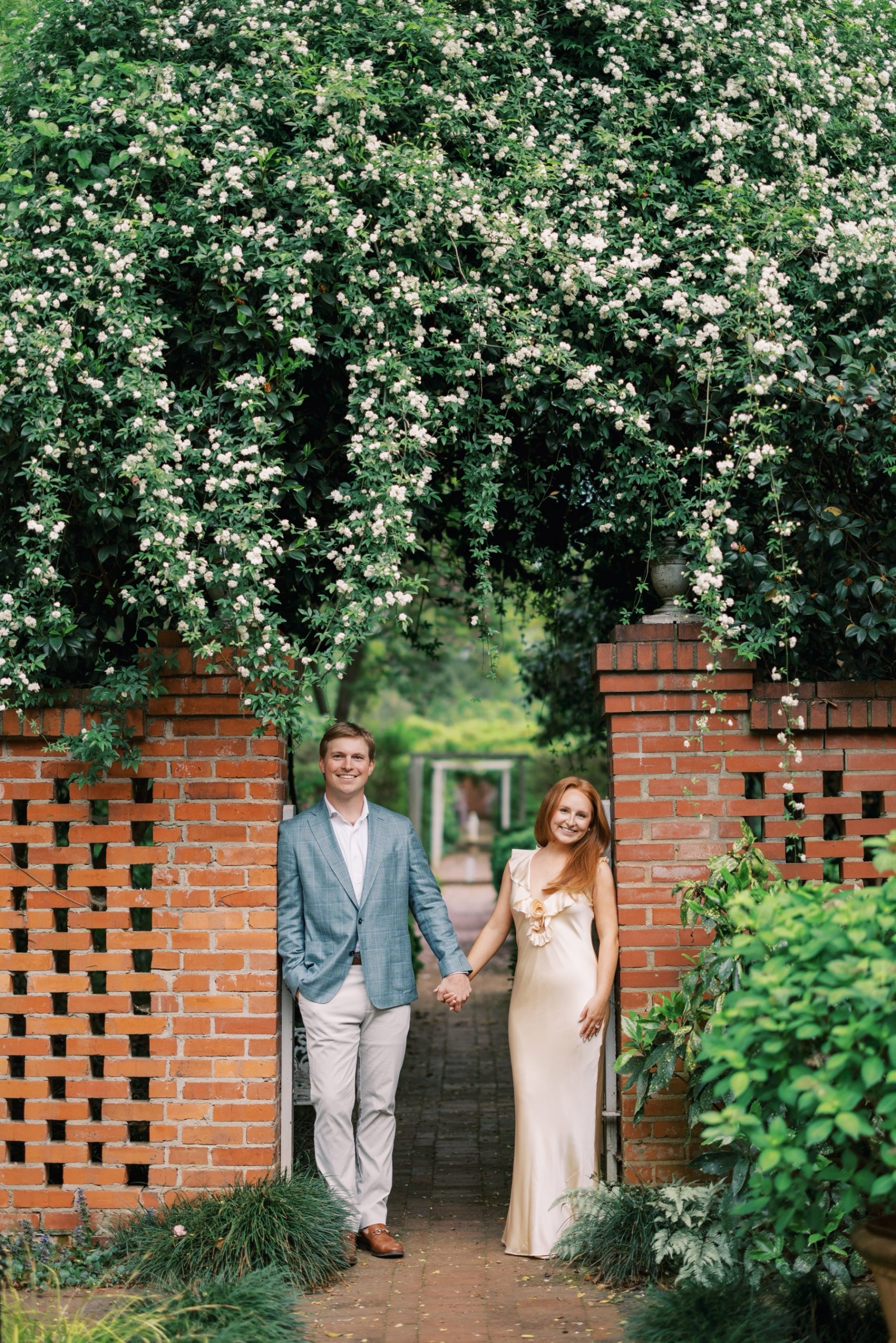 couple lean against brick entrance at garden 